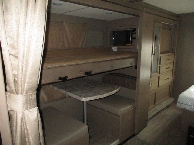 RV rental interior with a bunk bed, dinette, microwave, and dresser. Ideal family setup for travel adventures.. Thor Motor Coach Daybreak 2021