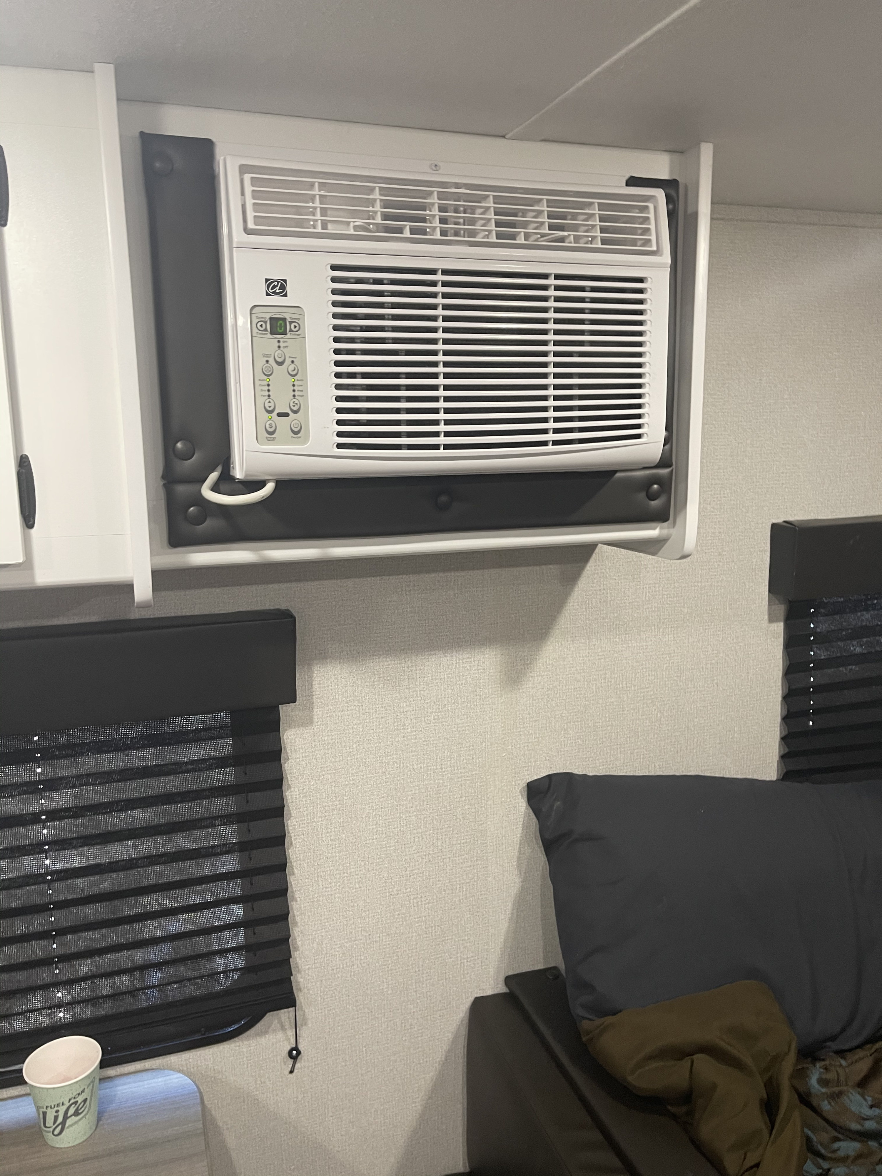 RV rental interior showing a compact air conditioner unit built into cabinetry, with window blinds and bedding visible.. keystone Hideout 2021