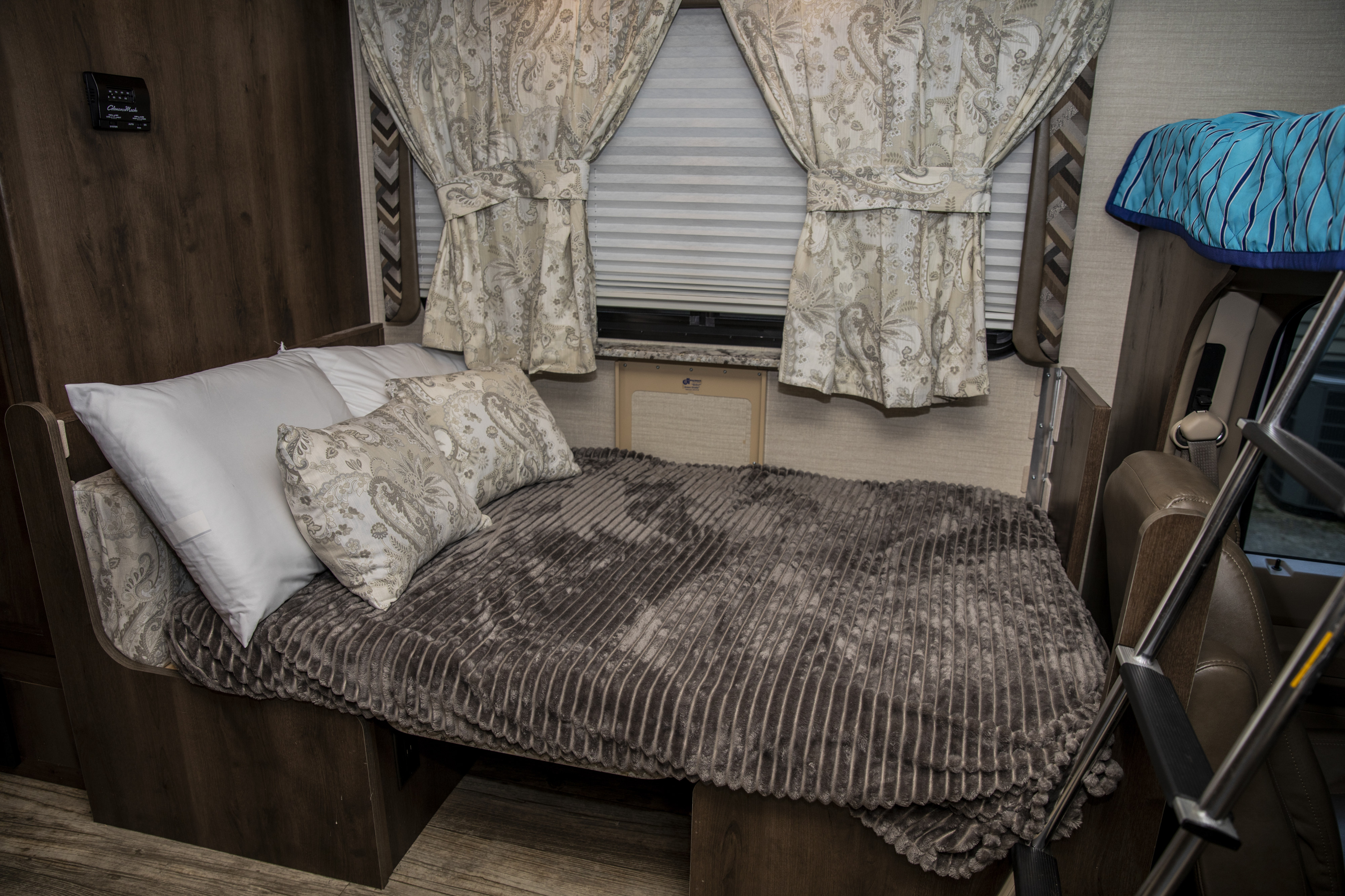 An inviting RV rental bedroom featuring a comfy bed with a soft brown blanket, white pillows, and elegant curtains.. Jayco Redhawk 2018