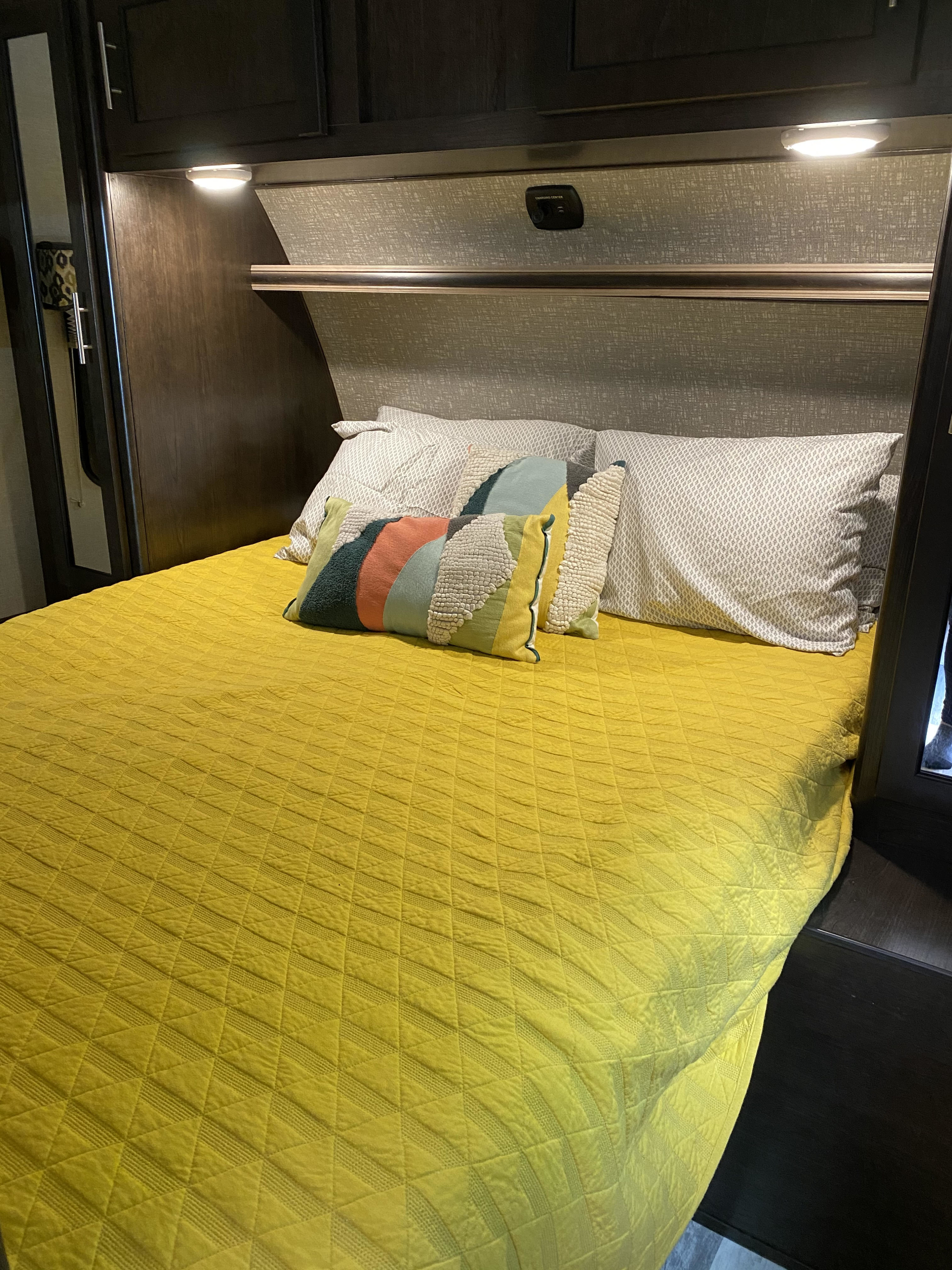 Cozy RV rental bedroom with bright yellow bed, textured pillows, and convenient charging center in a compact space.. Other Fun Finder 2017