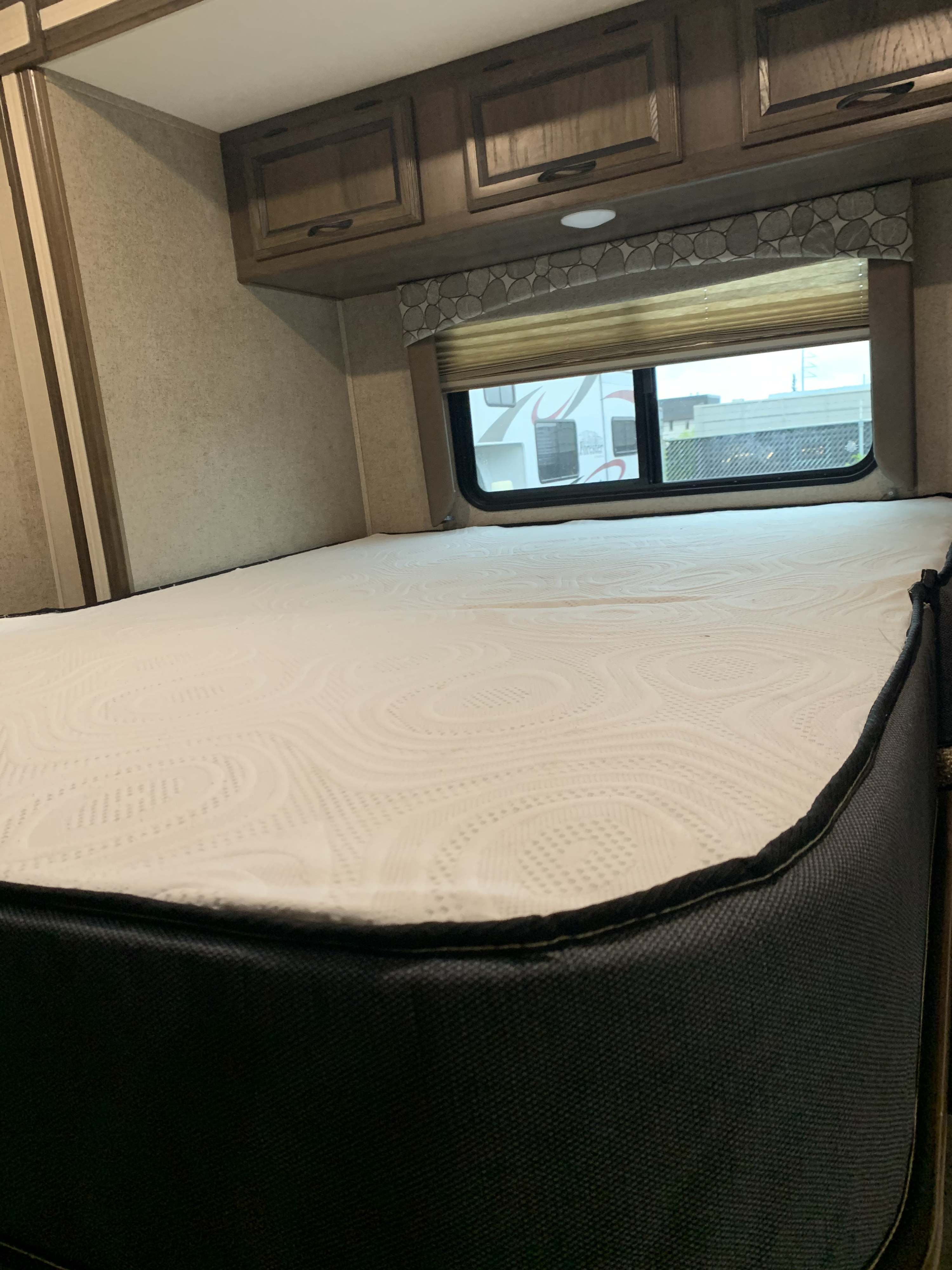 Comfortable RV rental bedroom with a fresh mattress, overhead cabinets, and a window view.. Coachmen by Forest River Freelander 2019