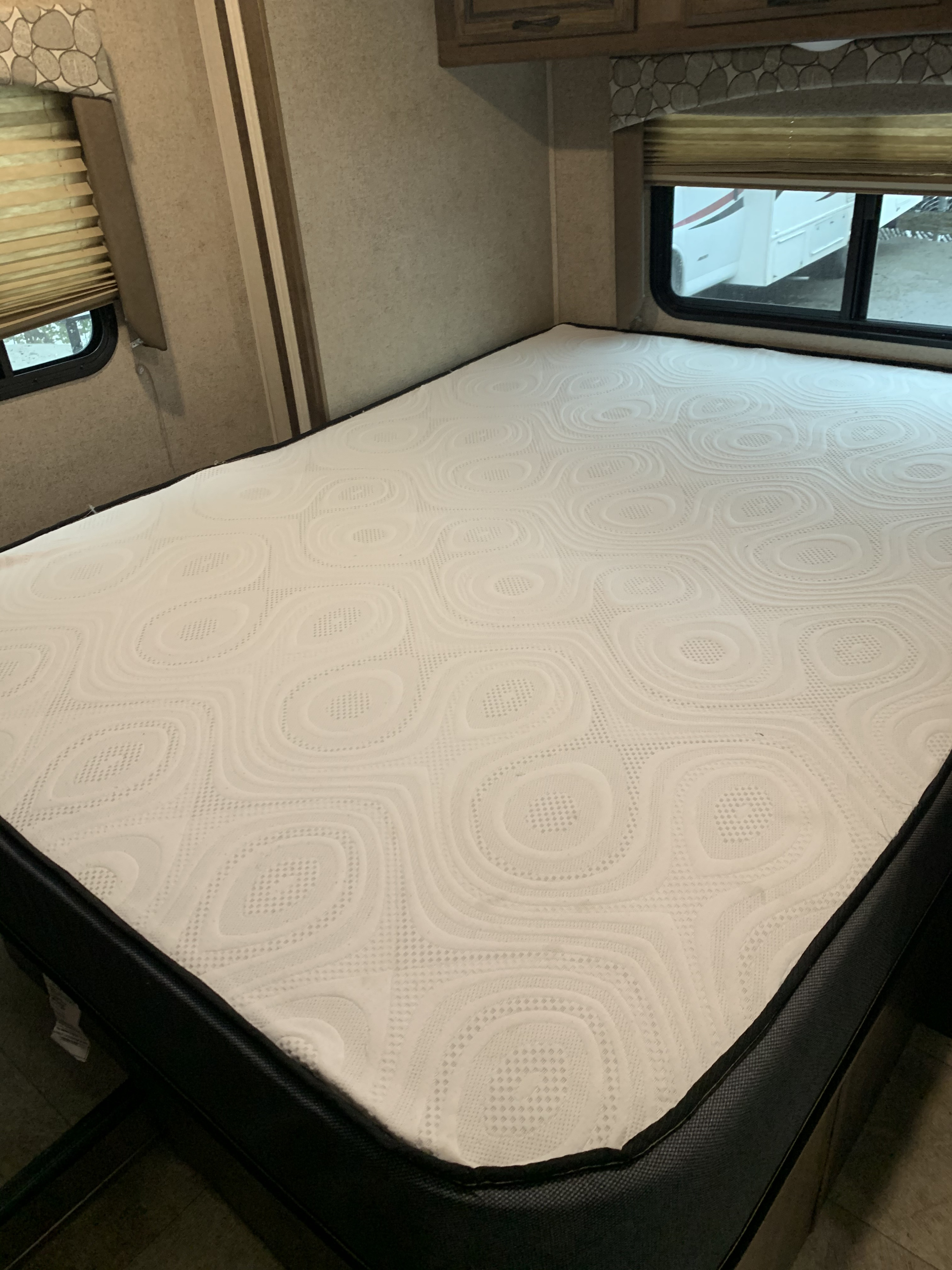 Comfortable RV rental bed with a patterned white mattress, ready for your travels. RV interior view.. Coachmen by Forest River Freelander 2019