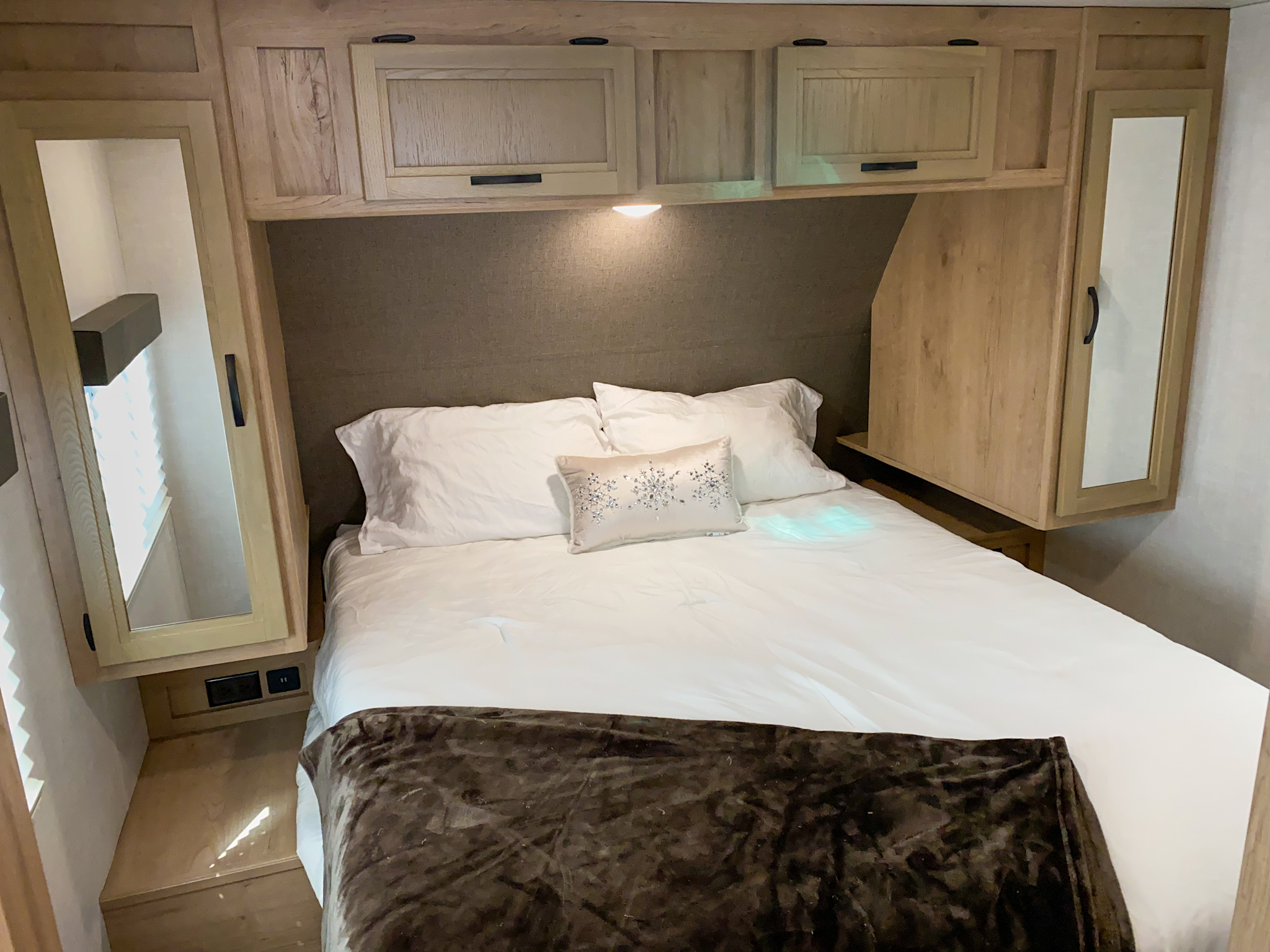 Cozy bedroom in an RV rental, featuring overhead storage, a comfortable bed, and convenient charging ports.. Winnebago Minnie 2021