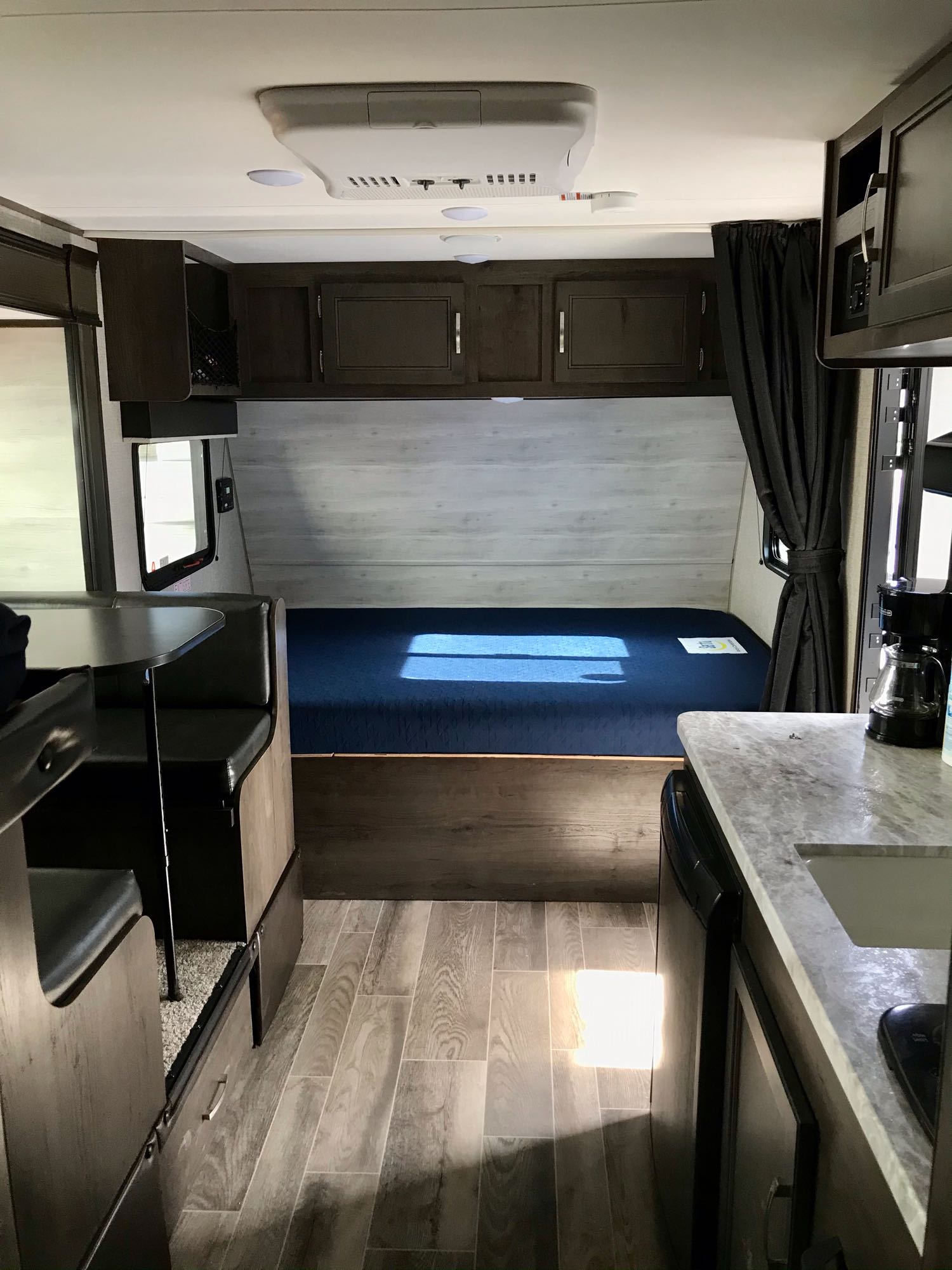 Inside this modern RV rental: cozy dinette, comfortable bed with blue mattress, and functional kitchen space.. Jayco Other 2021