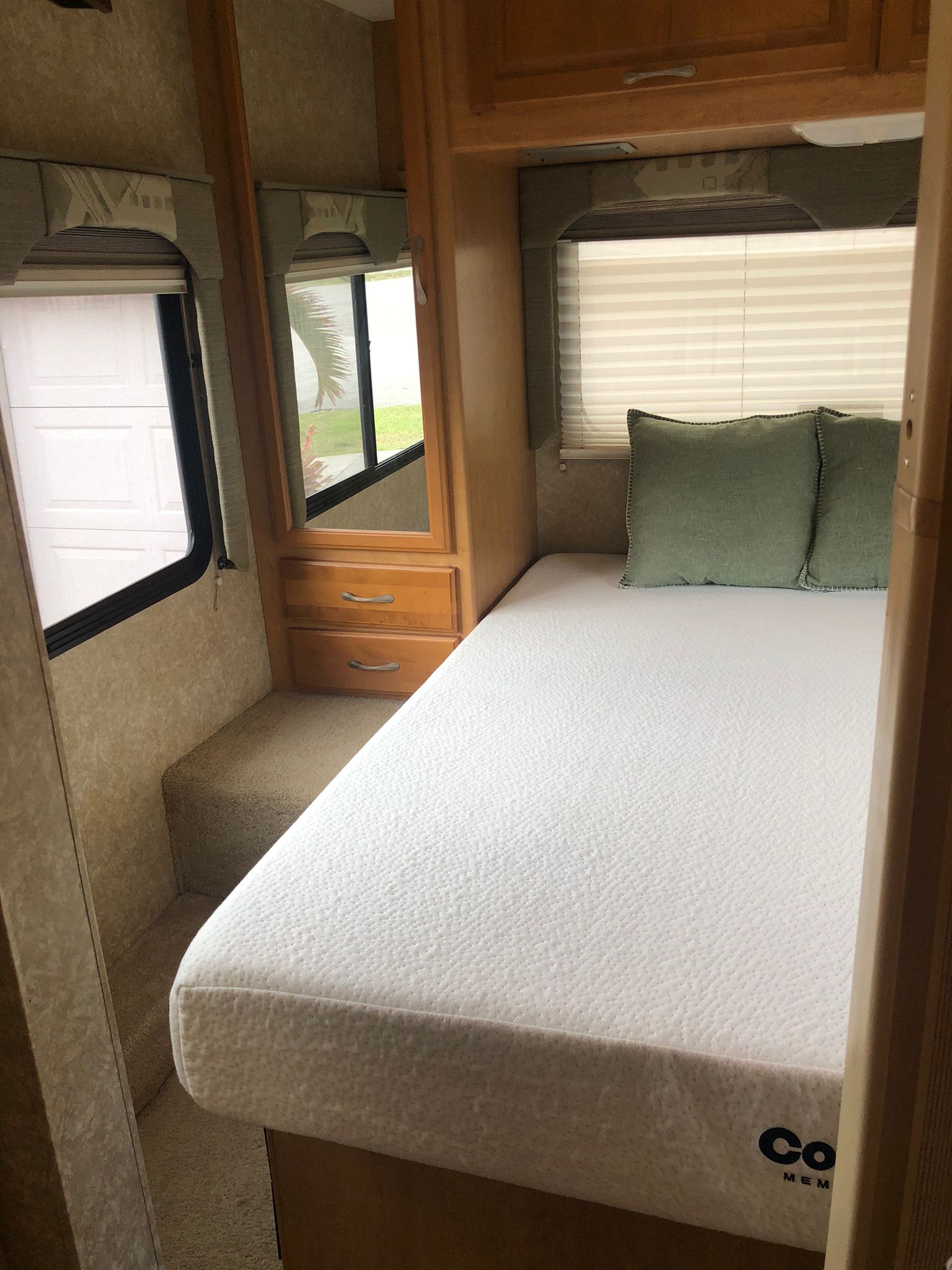 Cozy RV rental bedroom featuring a white mattress, green pillows, windows with blinds, and built-in storage.. Thor Motor Coach Four Winds Five Thousand 2007