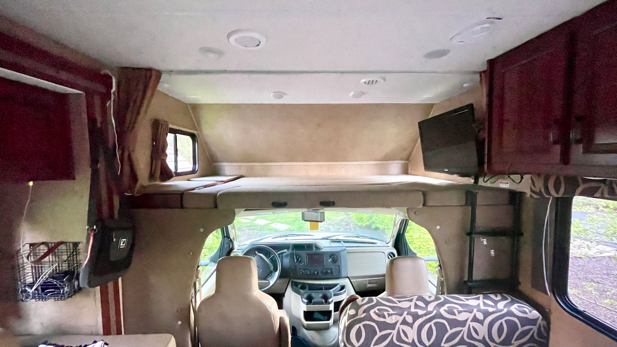 Spacious RV rental interior featuring an over-cab bunk, dashboard view, TV, and cabinets, perfect for your next trip.. Forest River Forester 2016