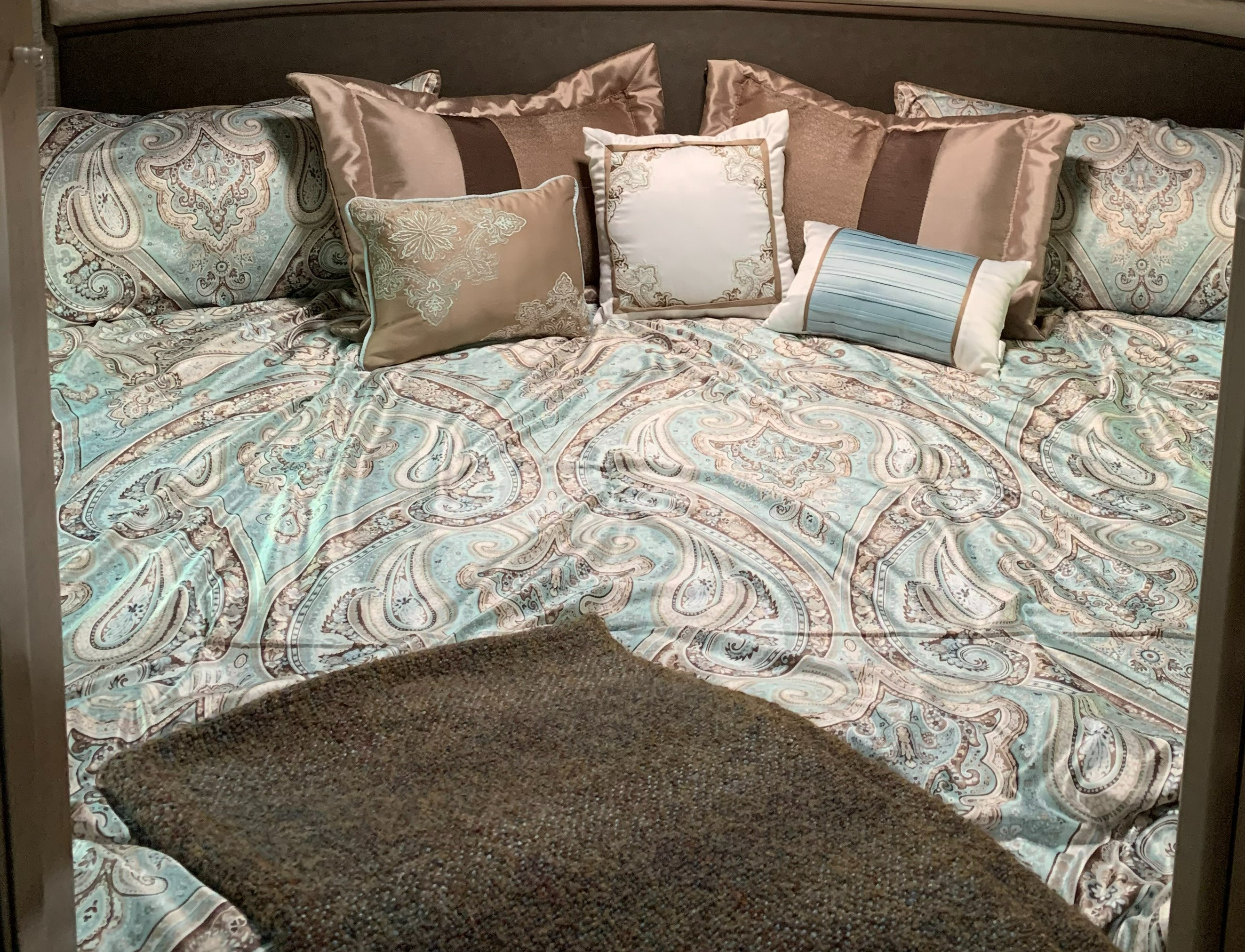 Plush RV rental bed features elegant teal paisley bedding and a variety of decorative pillows.. Thor Motor Coach Chateau 2021