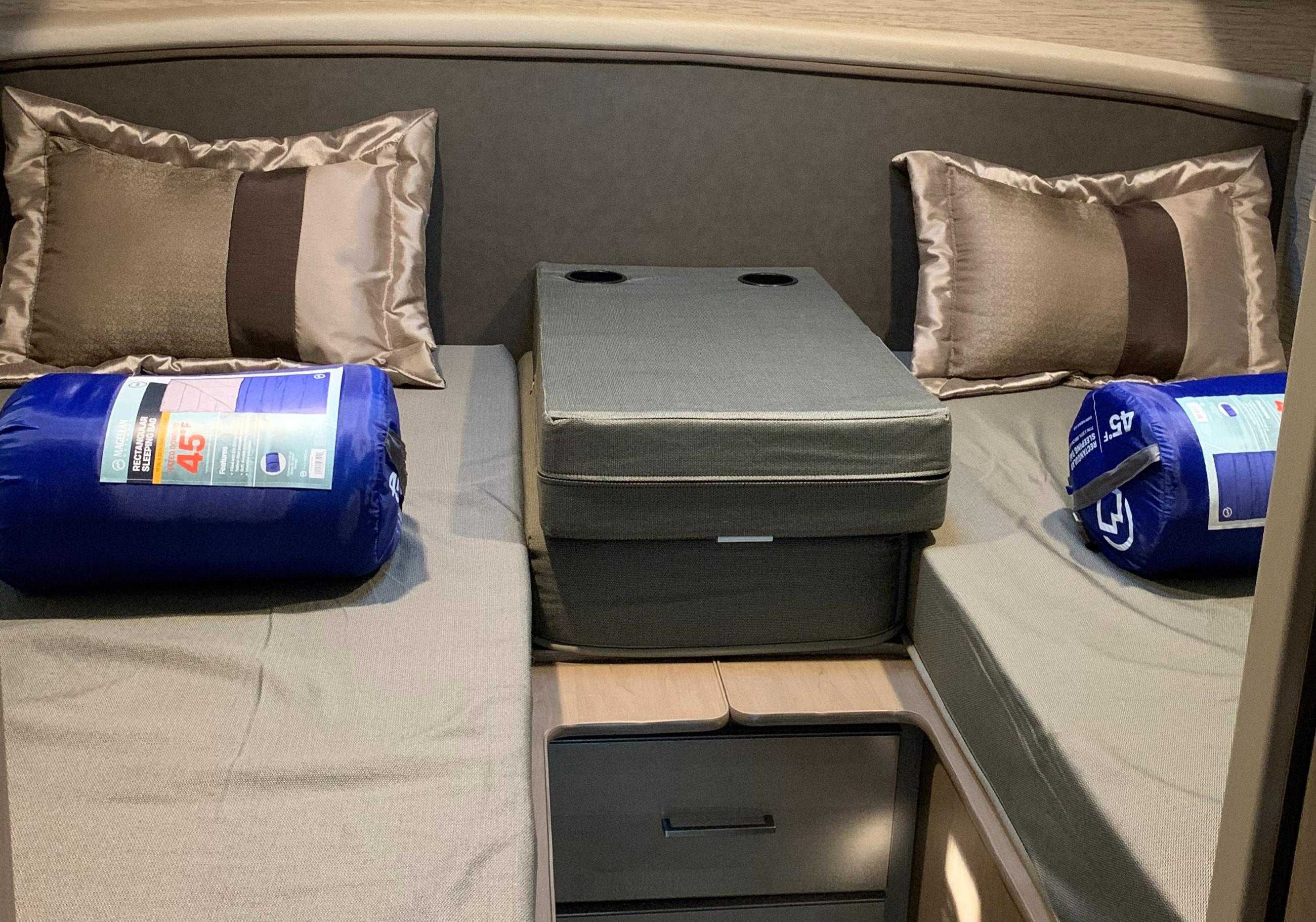 RV rental interior: two beds with pillows & rolled sleeping bags, plus a central console with cup holders & storage.. Thor Motor Coach Chateau 2021