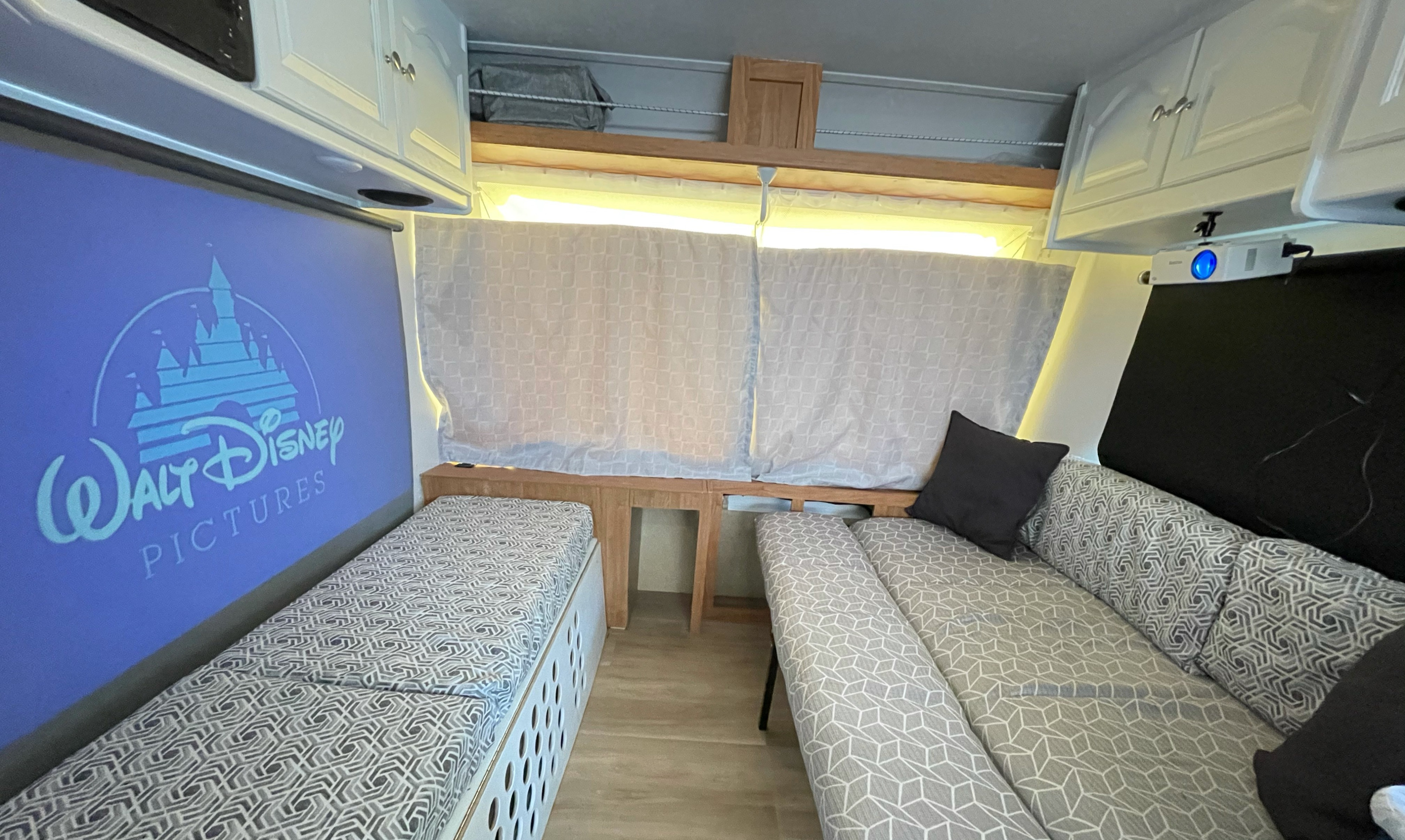 Cozy RV rental interior with a large projection screen for movies, comfortable seating, and smart storage solutions.. Forest River Rockwood Roo 2010