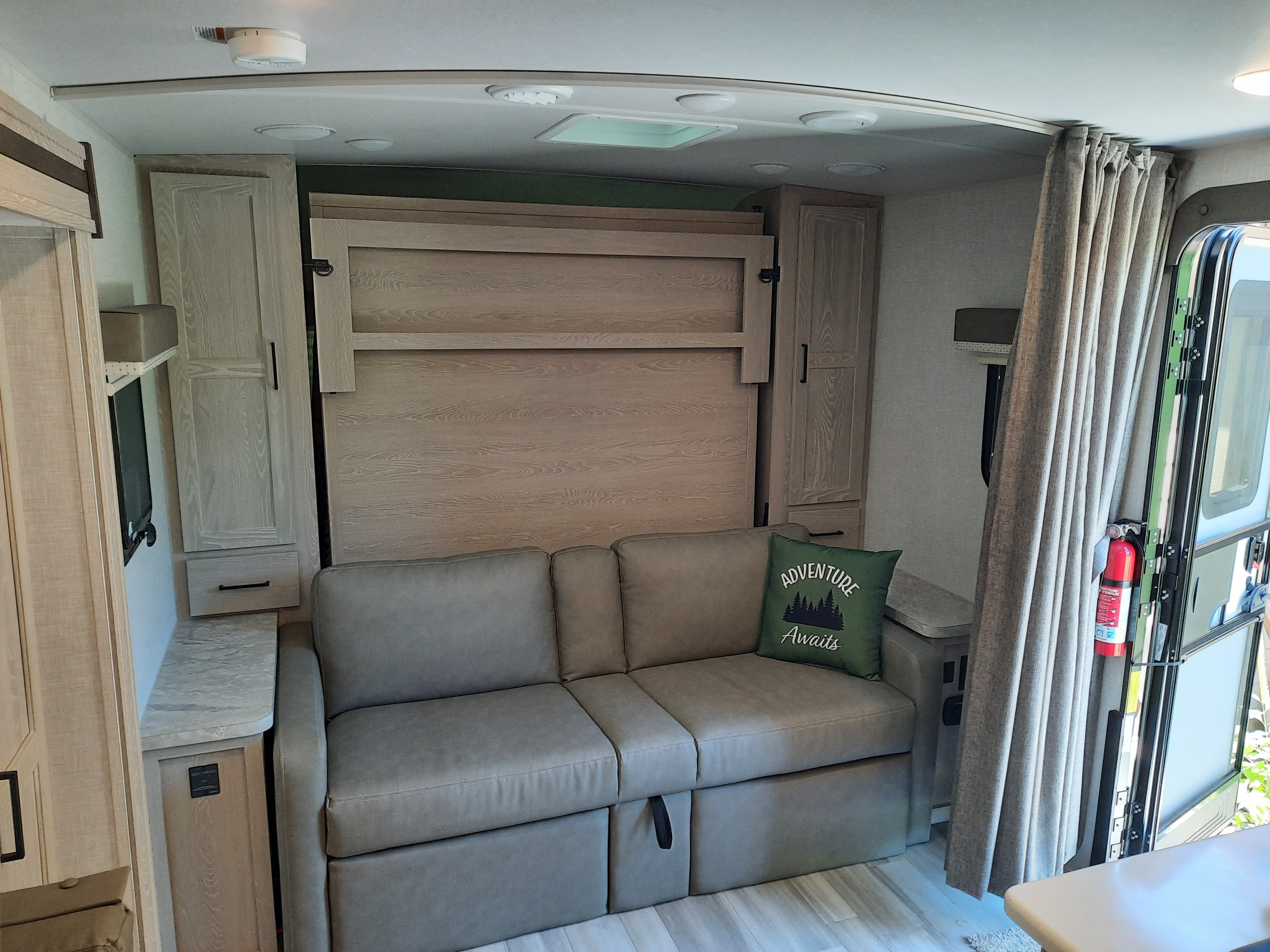 Cozy RV rental interior featuring a versatile sofa, murphy bed, and ample storage for travel.. Forest River Rockwood Mini Lite 2021