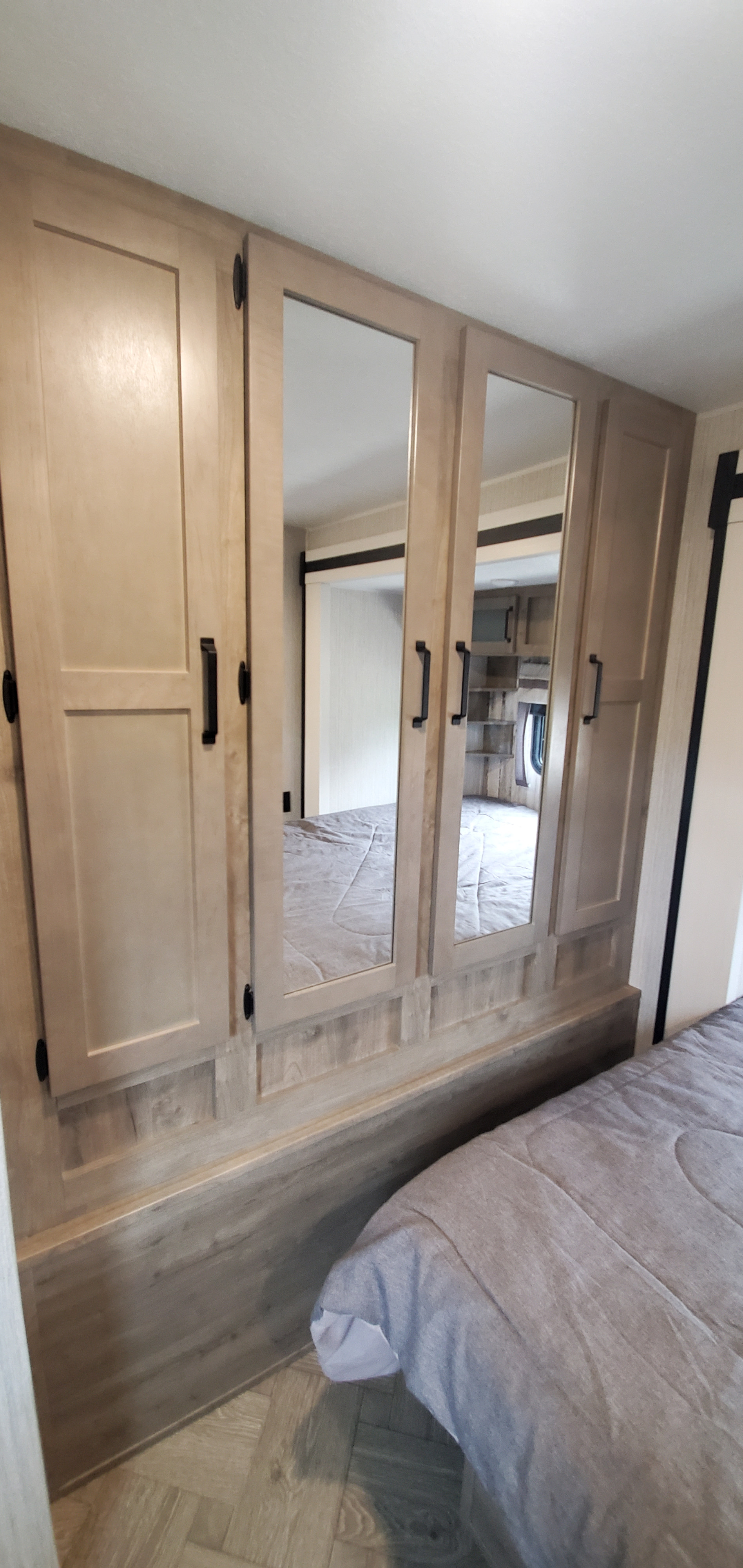 RV rental bedroom featuring light wood mirrored closet doors and a grey comforter on the bed.. Palomino Puma 2021