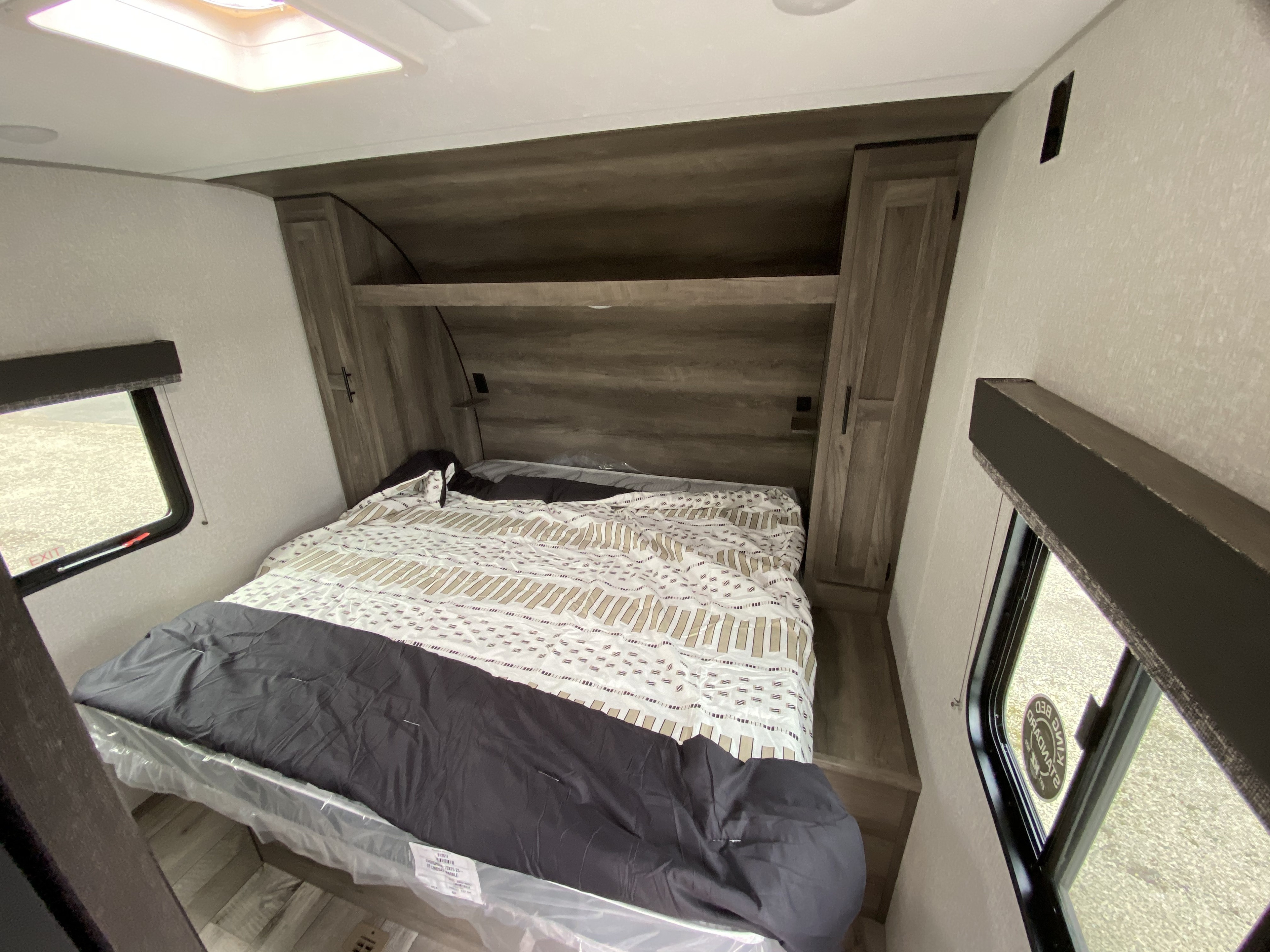 Spacious RV rental bedroom featuring a queen bed with new mattress, built-in storage, and side windows.. Sportsmen LE 2021