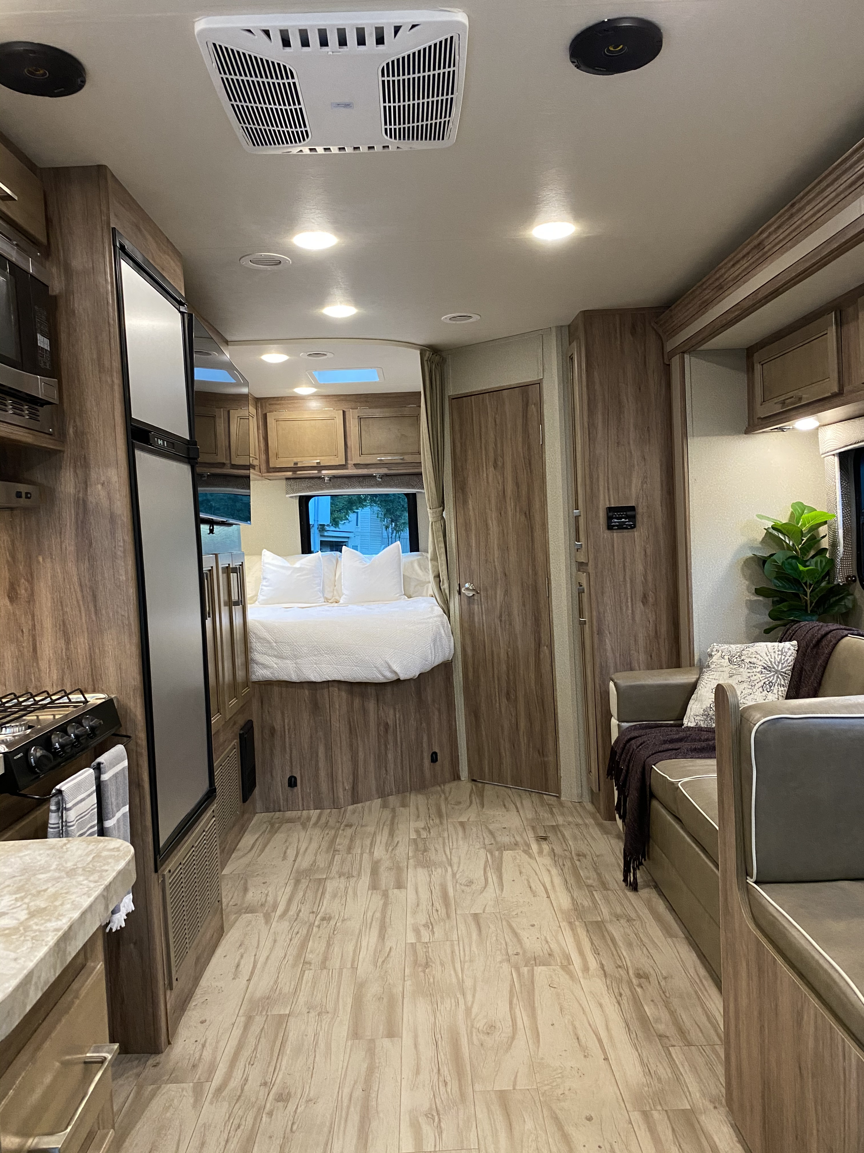 Modern RV rental interior: comfortable bed, compact kitchen with stove & fridge, and sofa. Great for road trips.. Entegra Coach Odyssey 2019