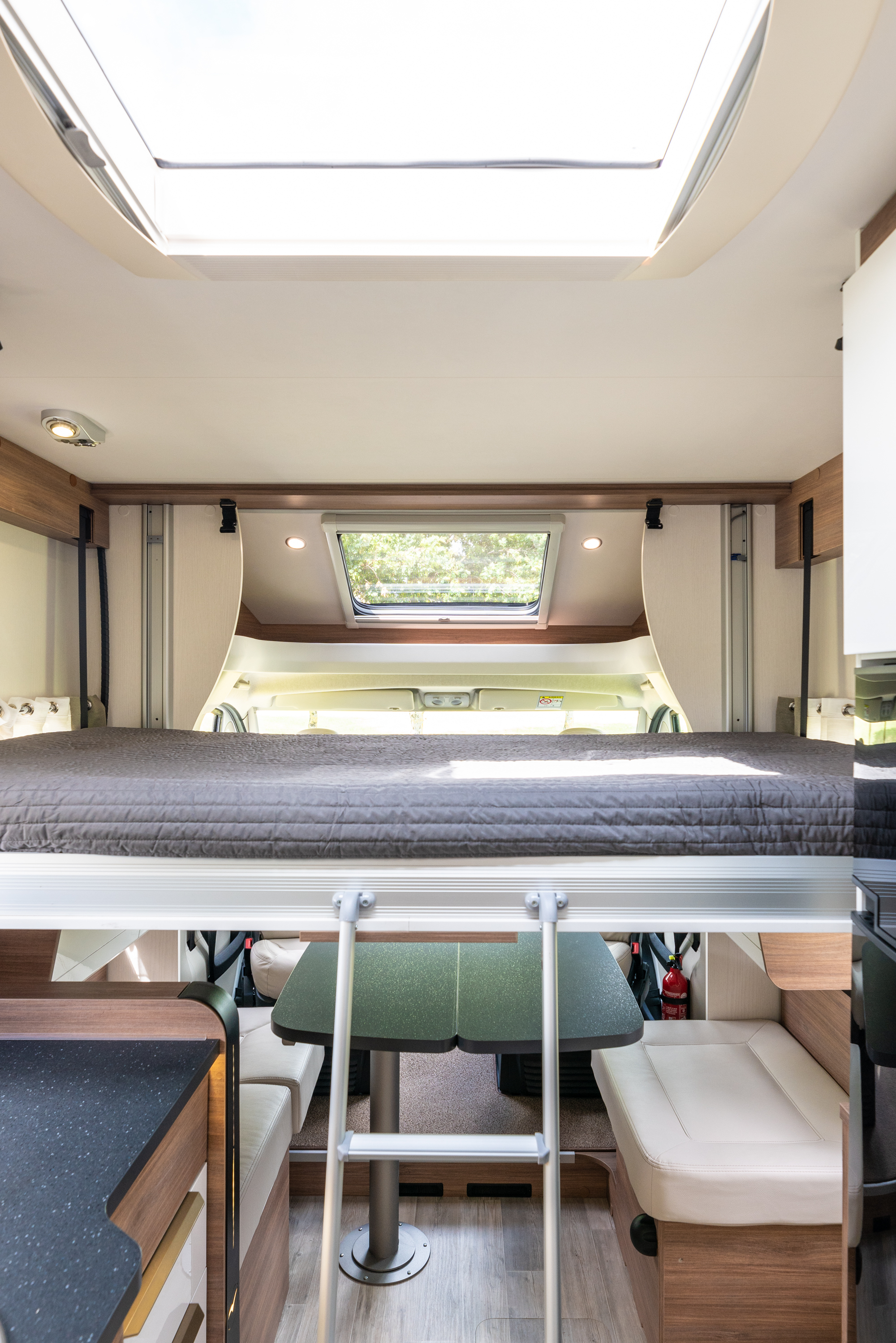 Spacious rv rental interior features a cozy bunk bed over a dining area, perfect for family adventures. Includes skylight and seating.. PILOTE P746C ESSENTIEL 2024