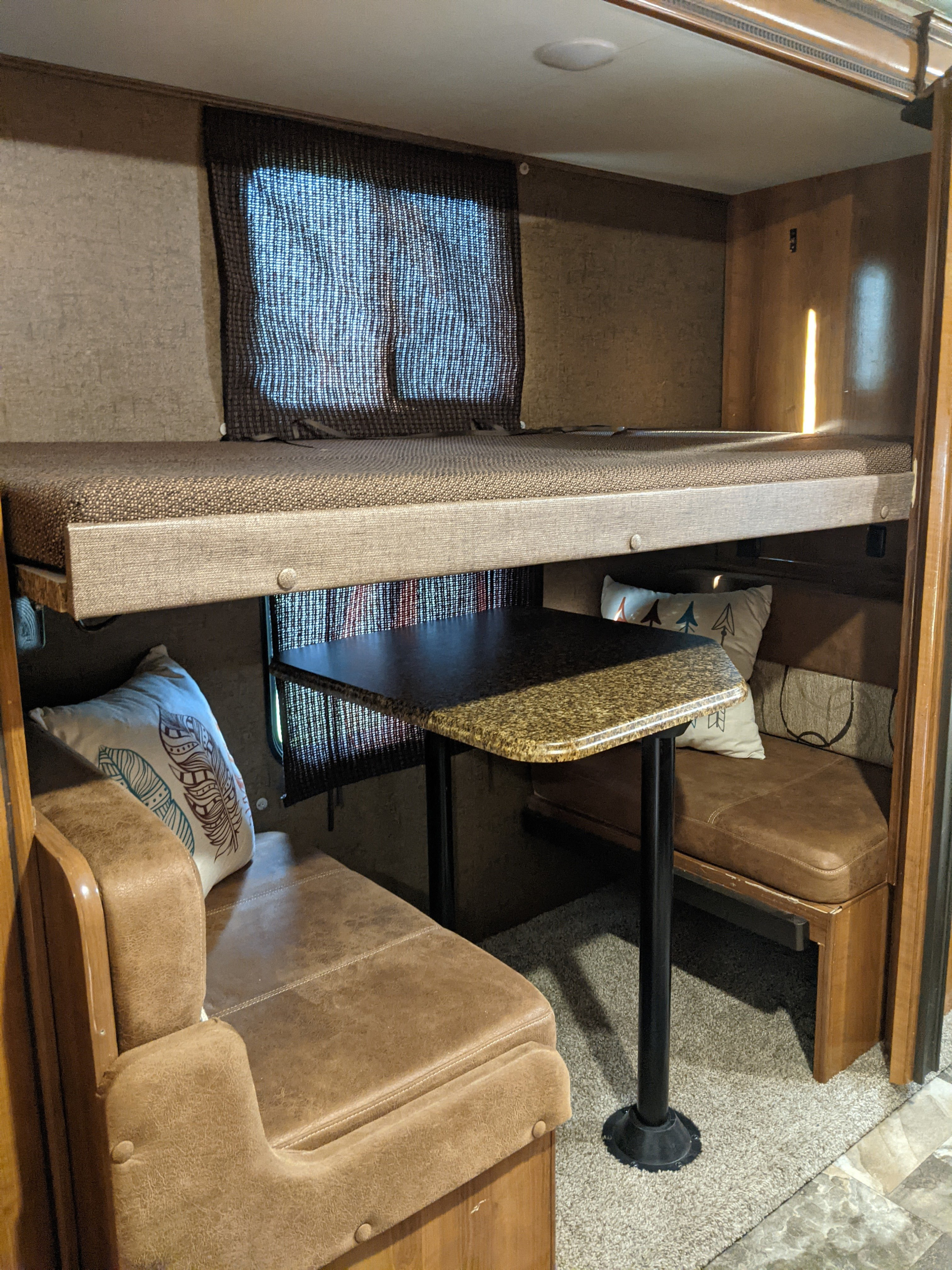 Cozy RV rental interior with bunk beds, dinette, and plush seating, perfect for travel adventures.. Coachmen Leprechaun 2018