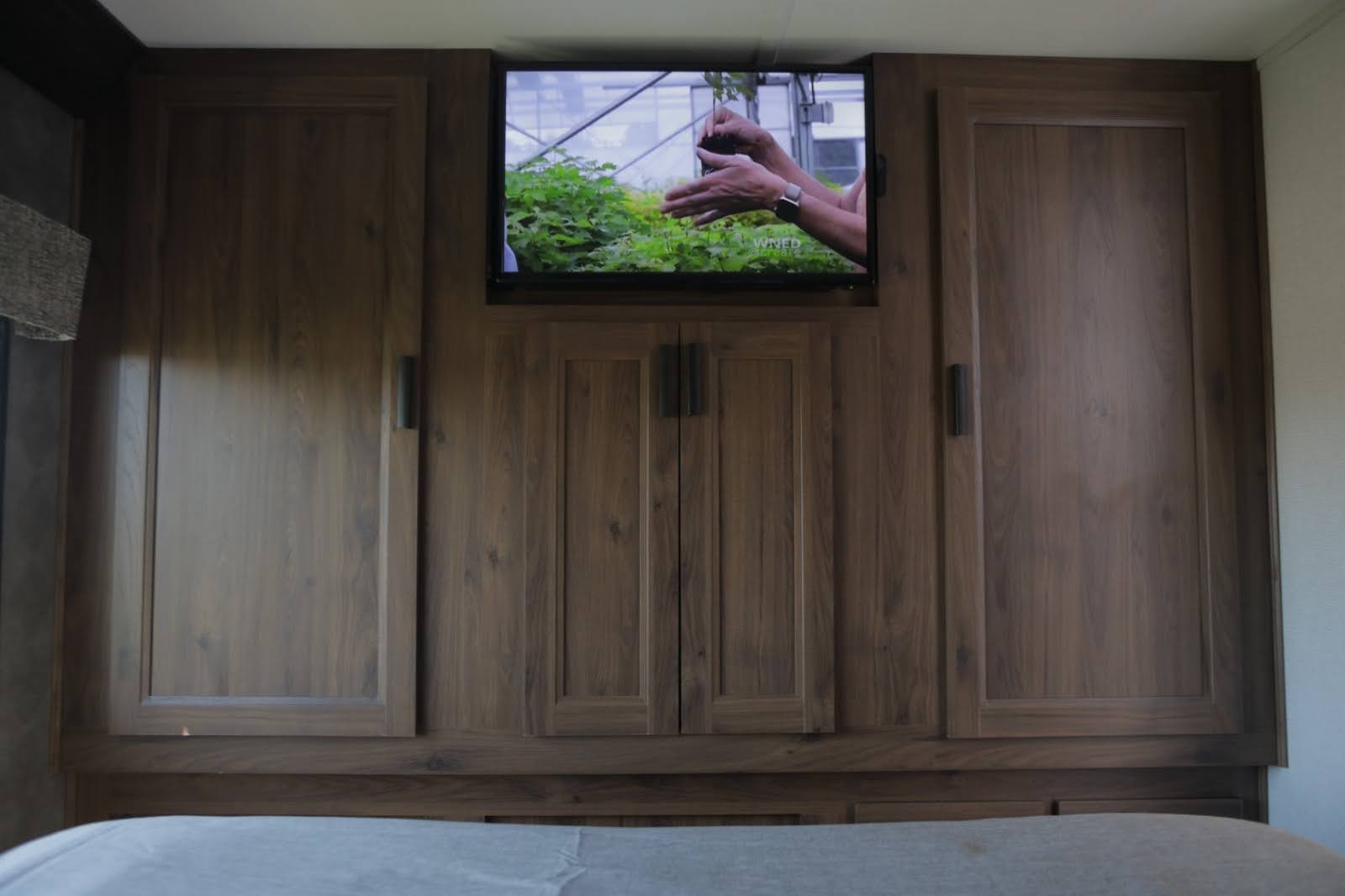 RV rental bedroom with ample wooden cabinetry, a TV, and under-bed storage for comfort and utility.. Forest River Other 2021