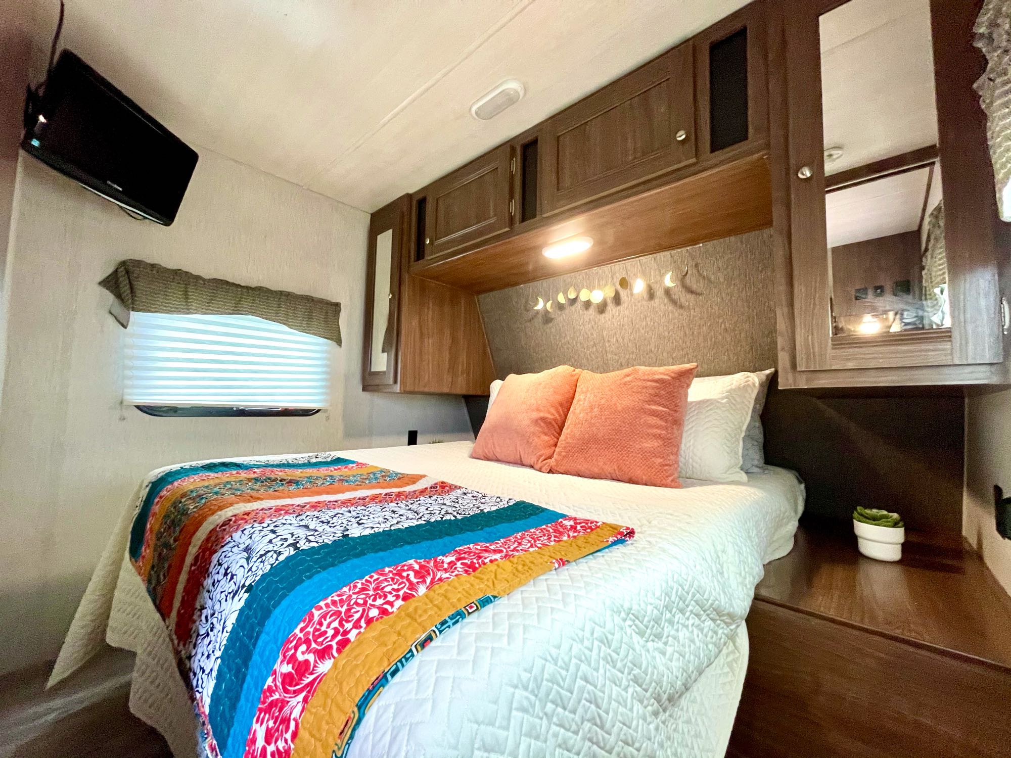 Experience a comfortable RV rental bedroom, featuring a colorful bed, wall-mounted TV, and ample storage.. Heartland Pioneer 2018
