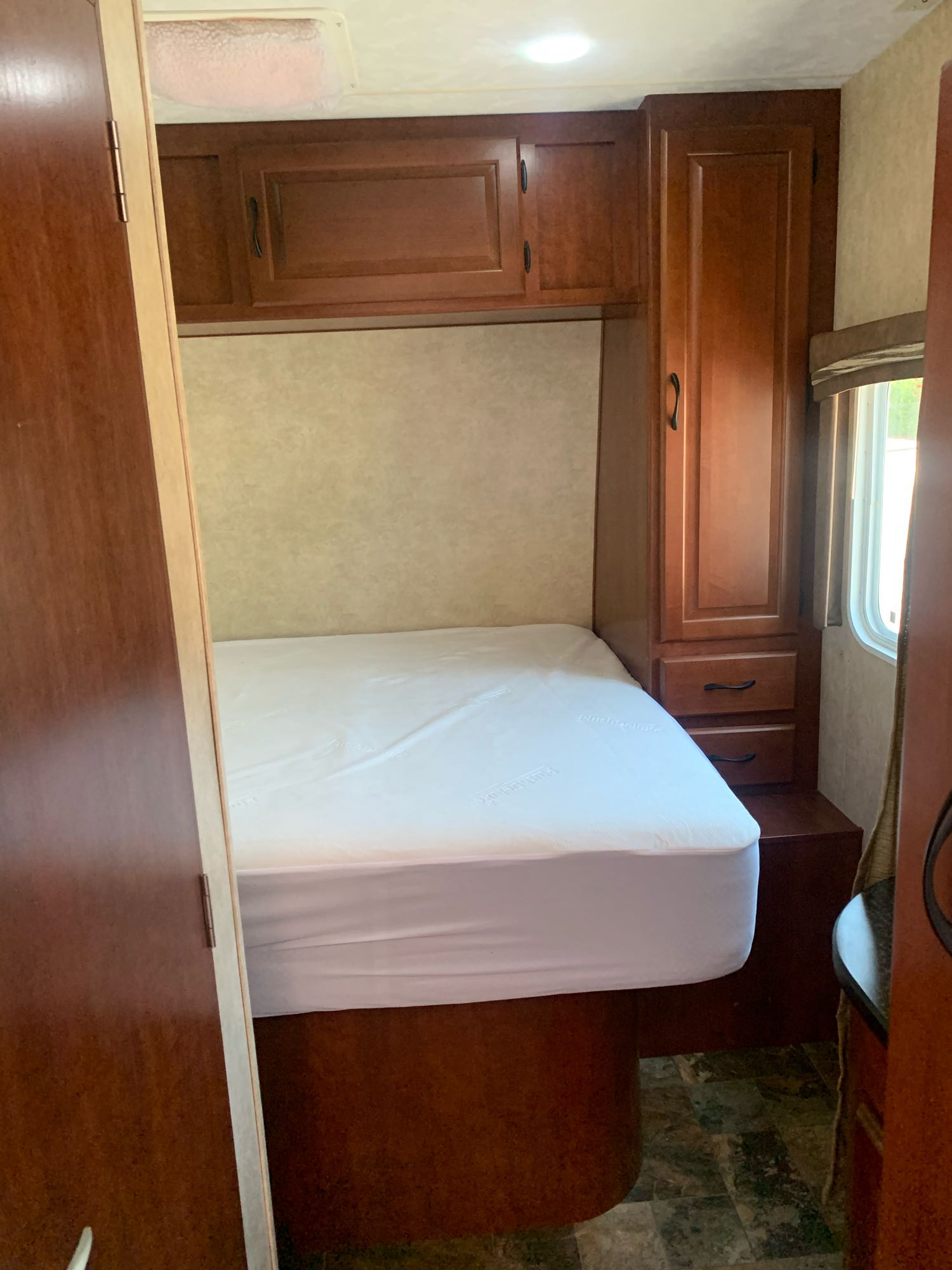 RV rental bedroom interior with a neatly made bed, wooden cabinets, and a window for comfortable travel.. Forest River Other 2013