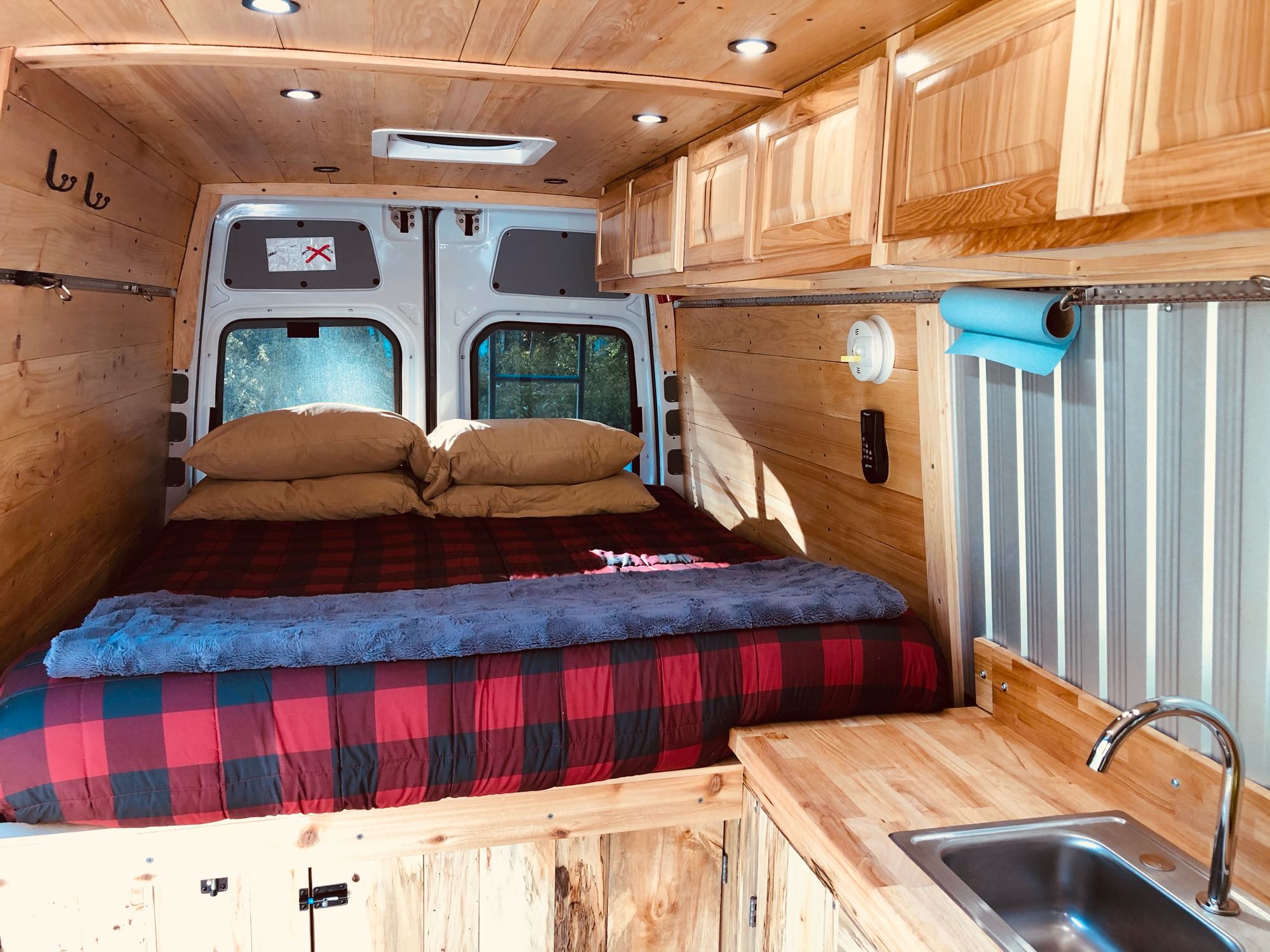 RV rental: This custom wooden van interior offers a cozy plaid bed & functional kitchen with sink, ideal for travel.. Mercedes Sprinter 2014