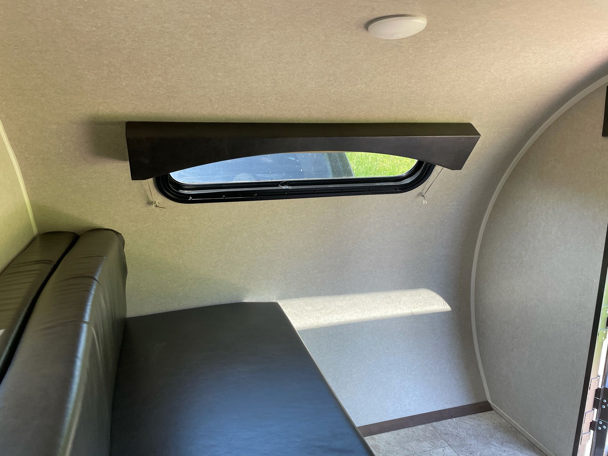 Inside an RV rental, showing a window with daylight, a ceiling light, and dark cushions forming a bed or bench area.. Sunray Other 2021