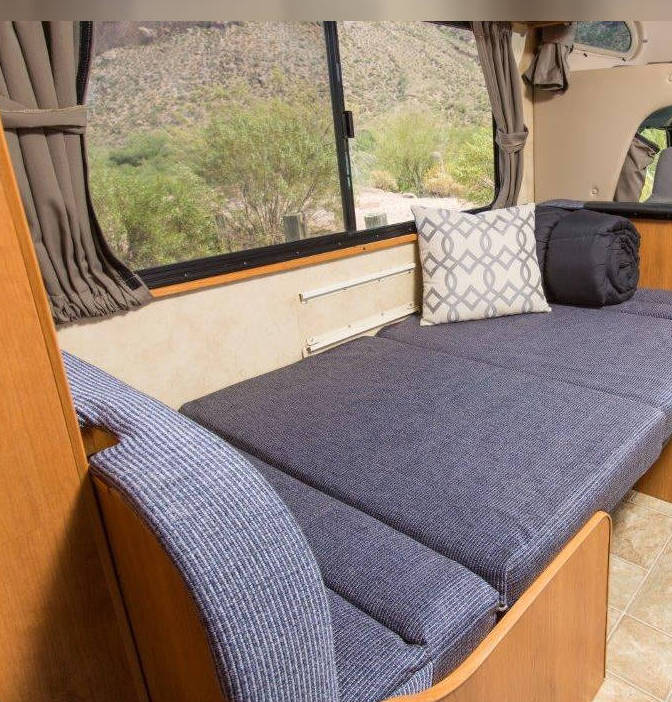 Comfortable RV rental interior with convertible bed/seating, decorative pillow, and scenic window views.. Thor Motor Coach Four Winds Majestic 2017