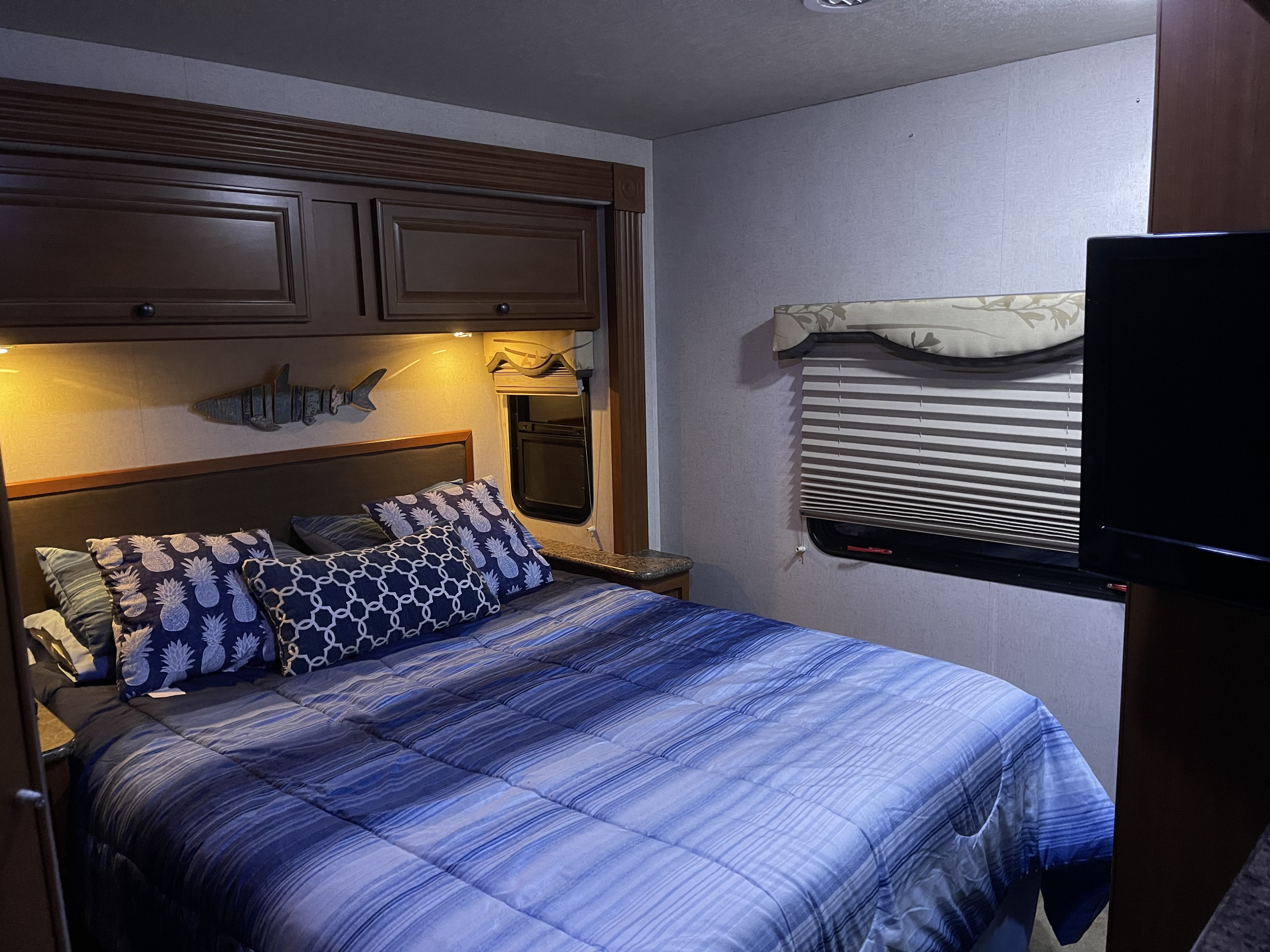 Comfortable RV rental bedroom featuring blue striped bedding, a shark decor, and ample overhead storage.. Other Other 2010
