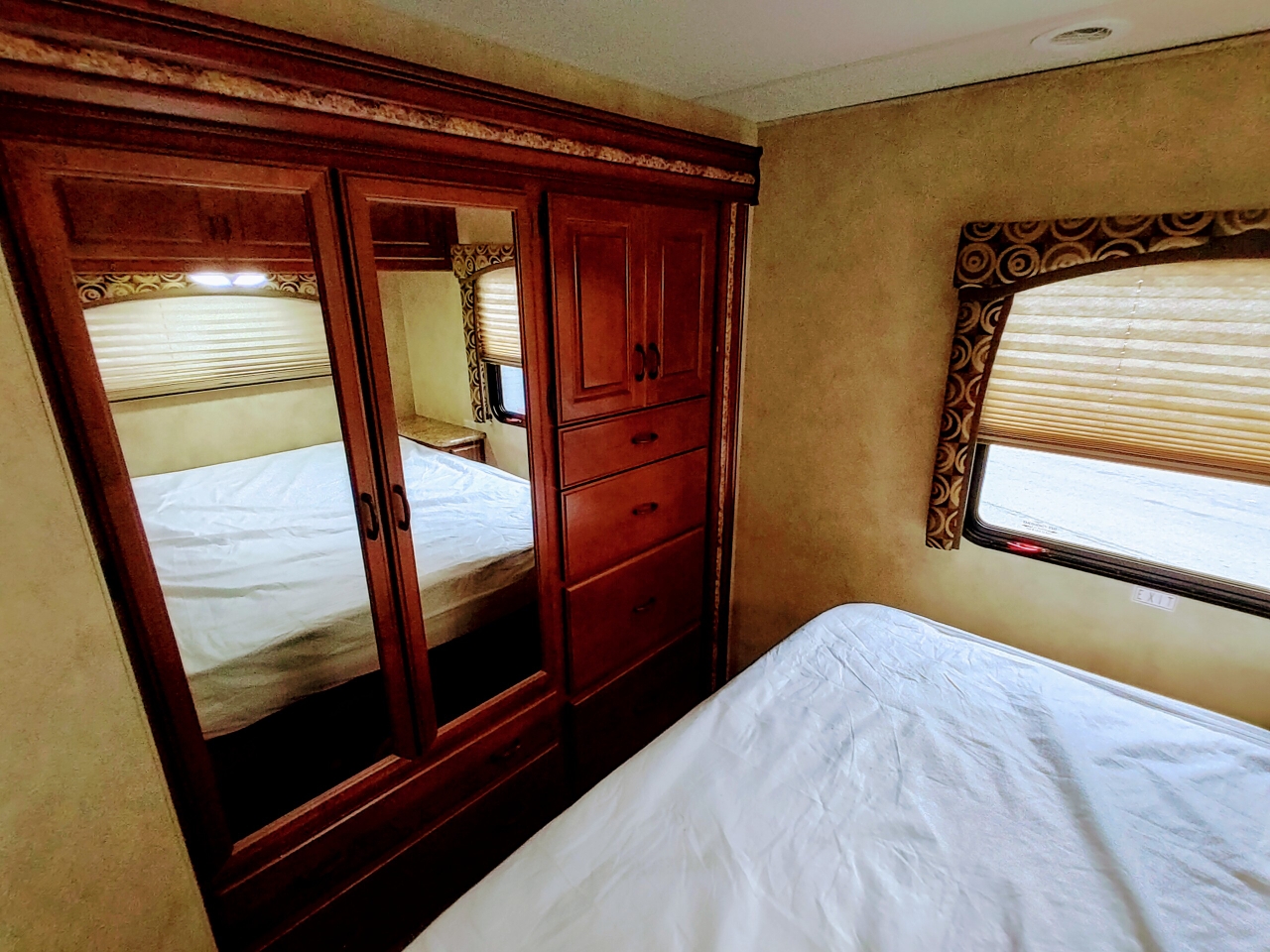 RV rental bedroom featuring a large mirrored closet reflecting the bed, a comfortable sleeping area, and a window.. Thor Motor Coach Hurricane 2011