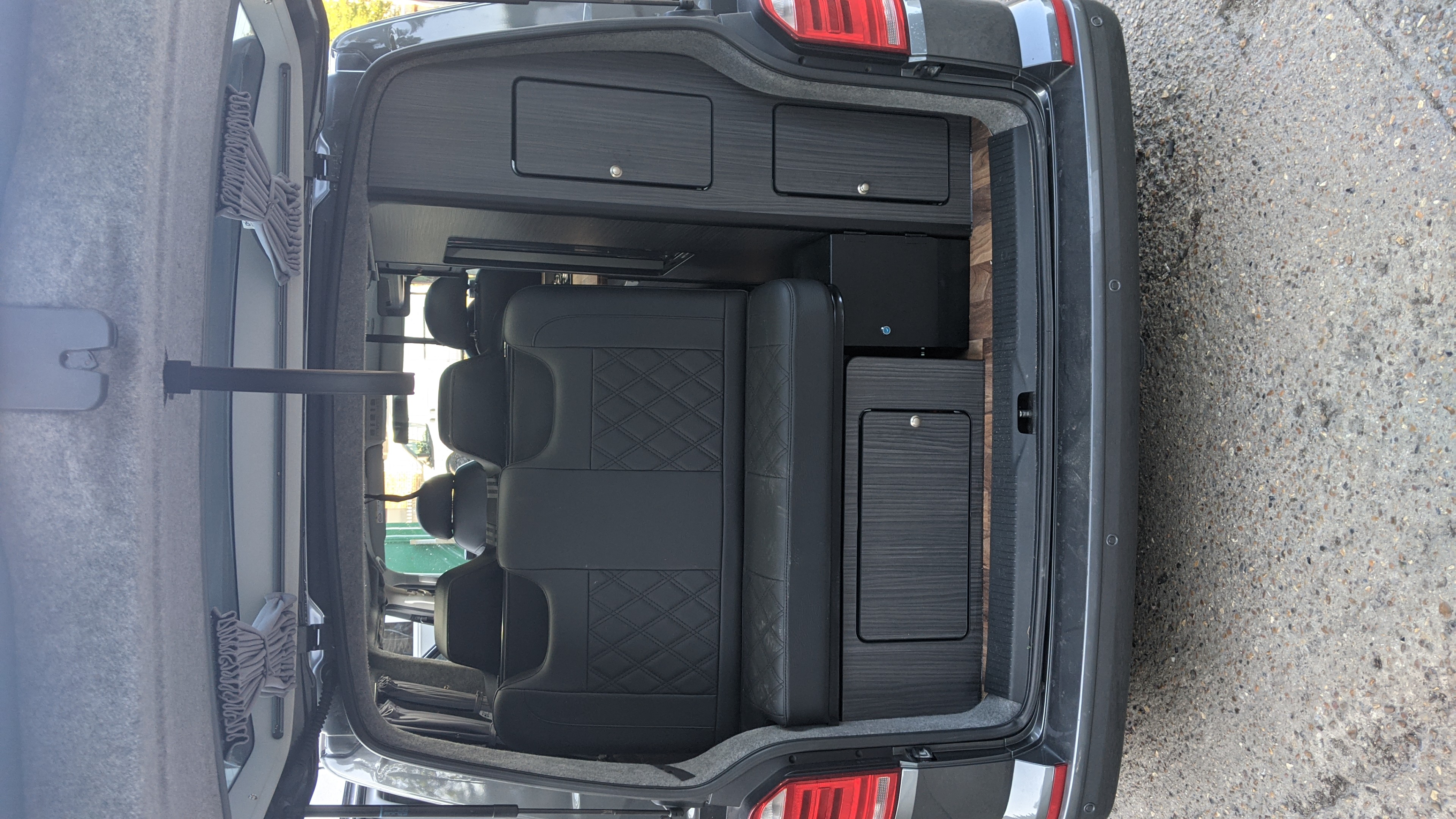 RV rental camper van interior: rear view of comfortable seating, wood-look flooring, and built-in storage cabinets.. vw T6 2016