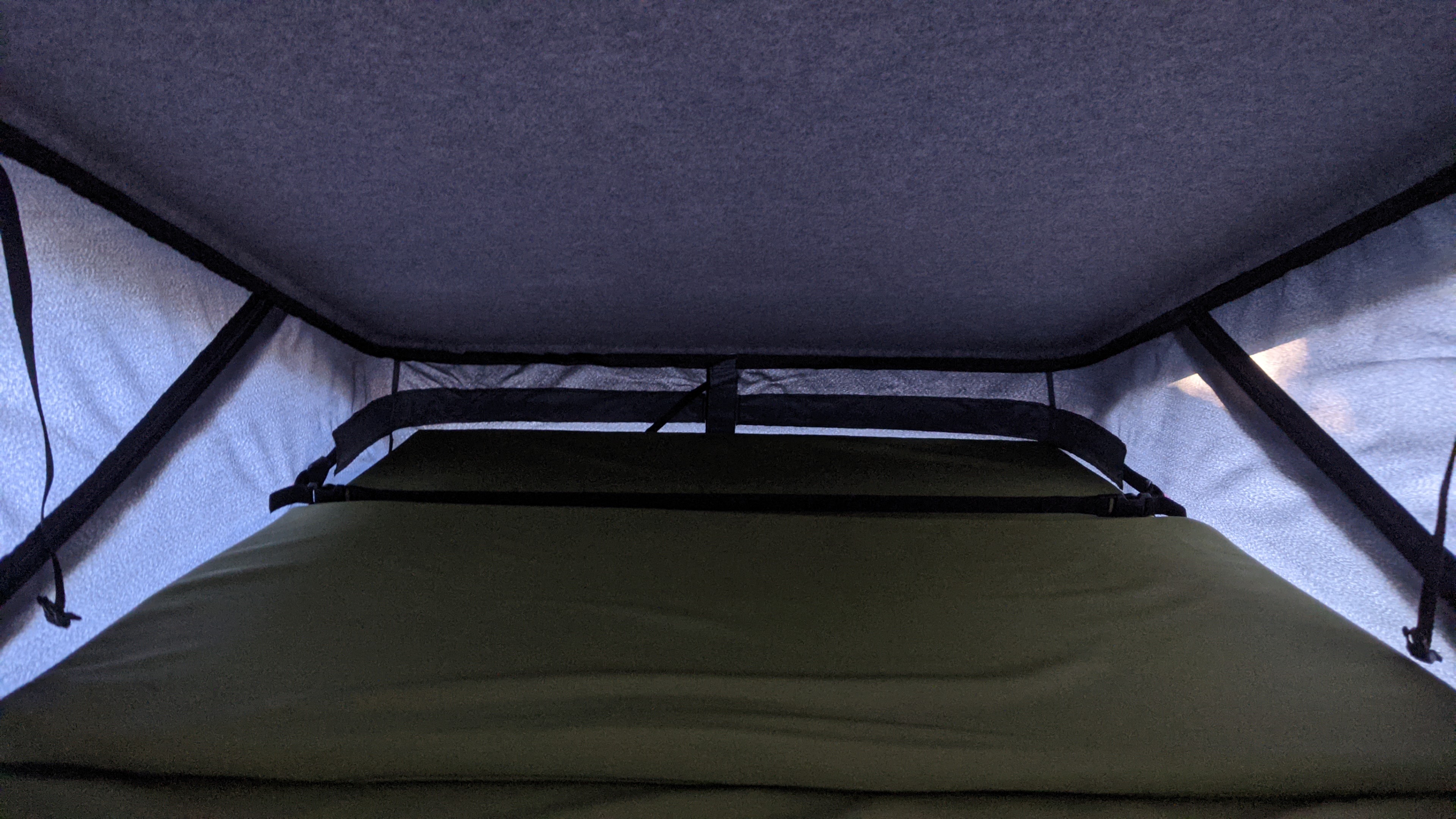 Cozy sleep area in an RV rental! View inside a pop-top tent with a green mattress and gray padded ceiling.. vw T6 2016