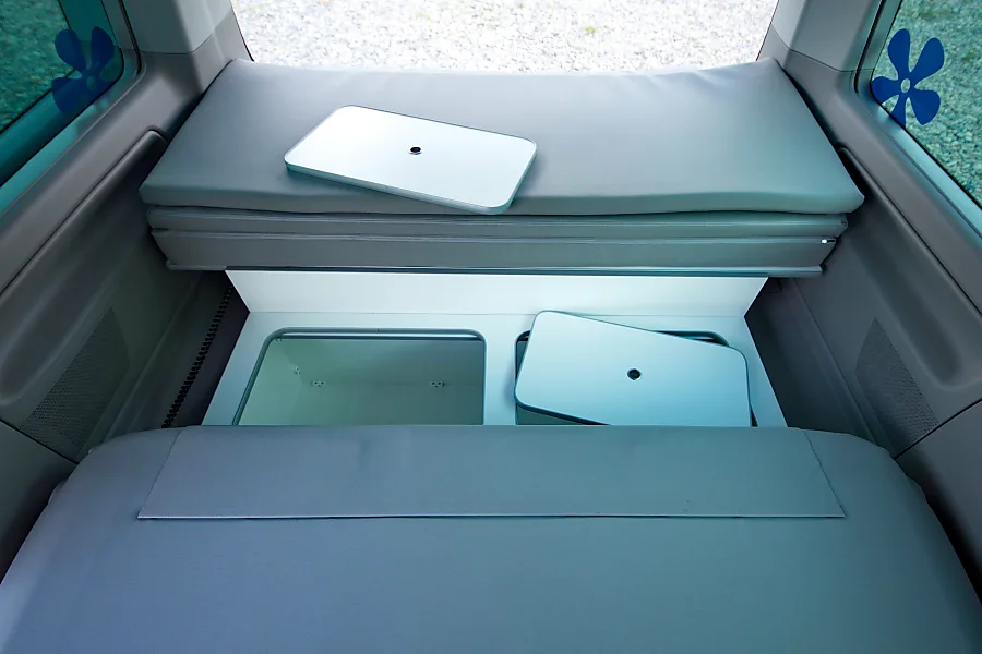 RV rental interior showcasing a versatile sleeping area with cushions and under-bed storage, including detachable table tops.. Volkswagen California Beach T6.1 2023