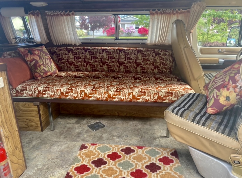 Cozy vintage RV rental interior, featuring a patterned sofa bed, decorative pillows, and a colorful rug.. Frontier Other 1979