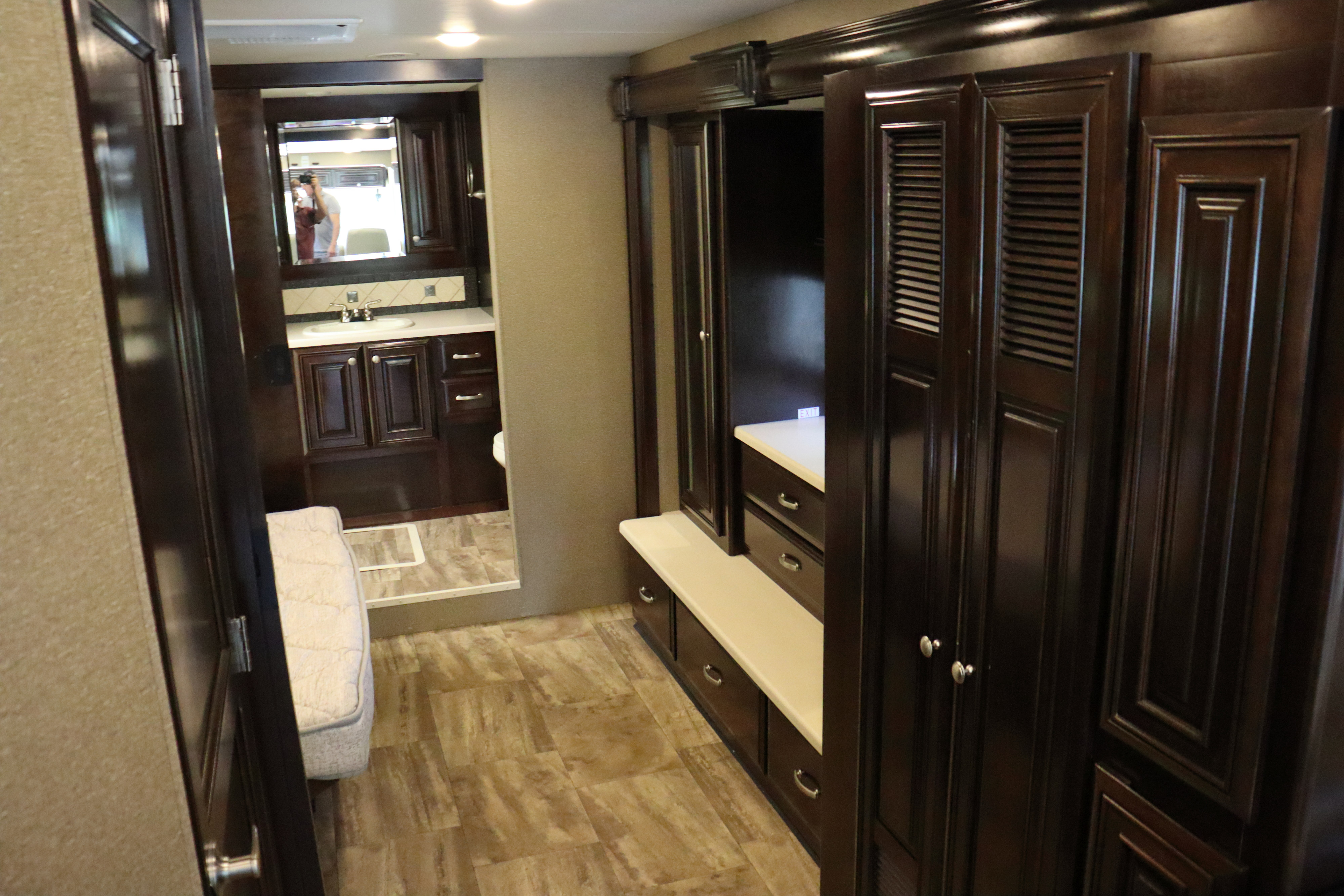 Modern RV rental interior: dark wood cabinetry, integrated storage, and a view into the compact bathroom.. Thor Motor Coach Palazzo 2016