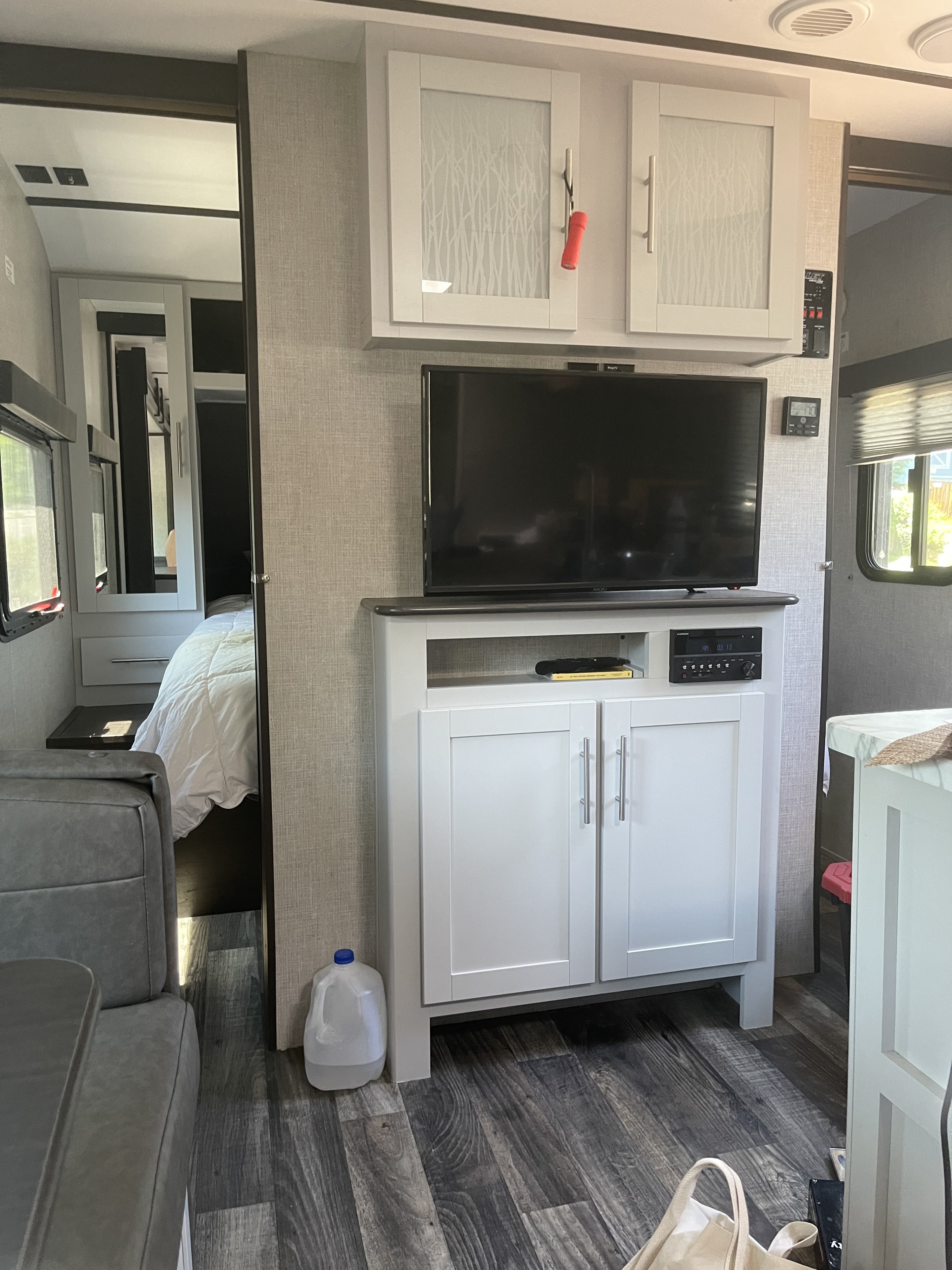 RV rental interior showing a clean living space with an entertainment center, TV, and access to a cozy bedroom.. Work and Play Work and Play Trailer 2020