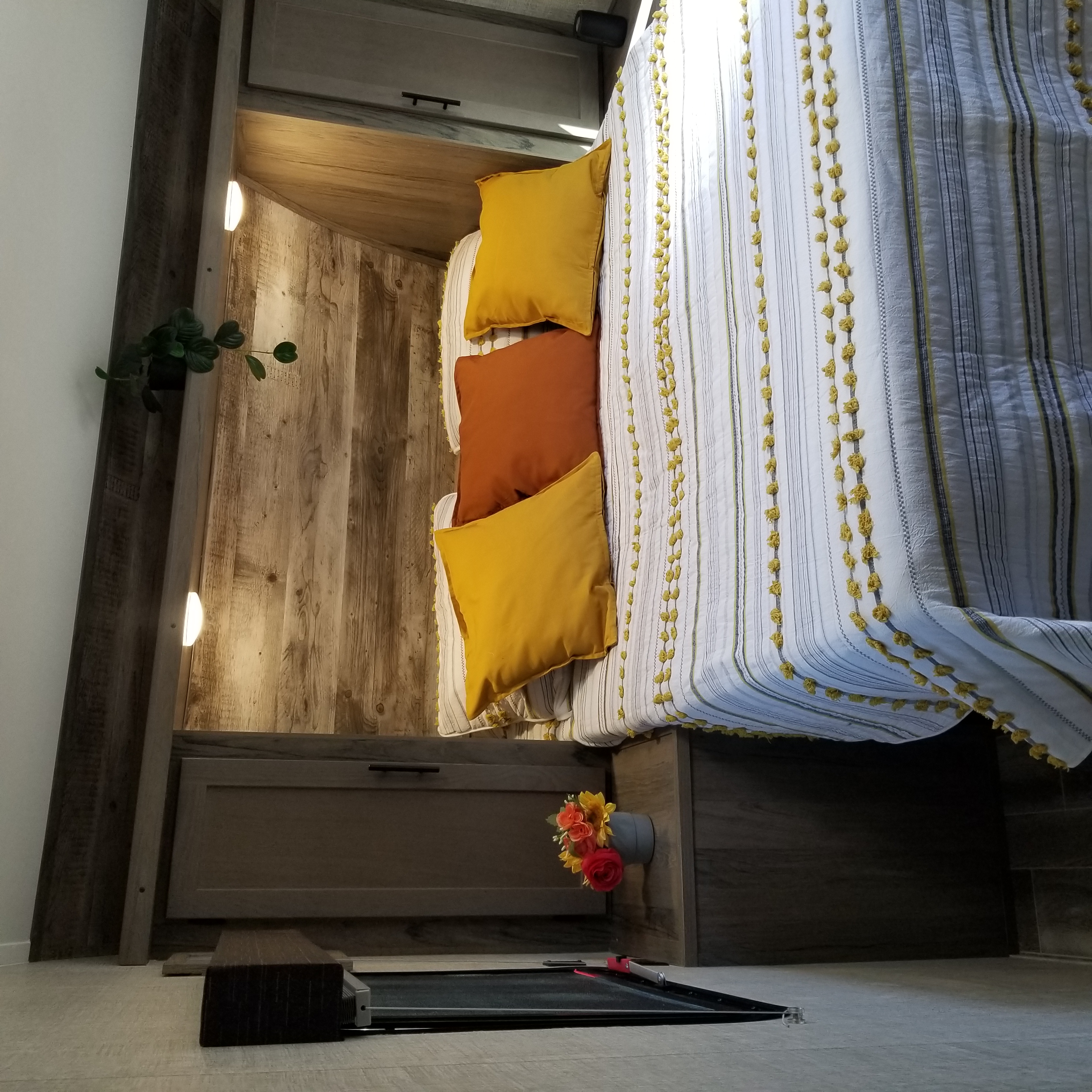 Modern RV rental bedroom interior with a cozy bed, bright yellow and striped bedding, and stylish wood paneling.. Gulf Stream Amerilite 2021