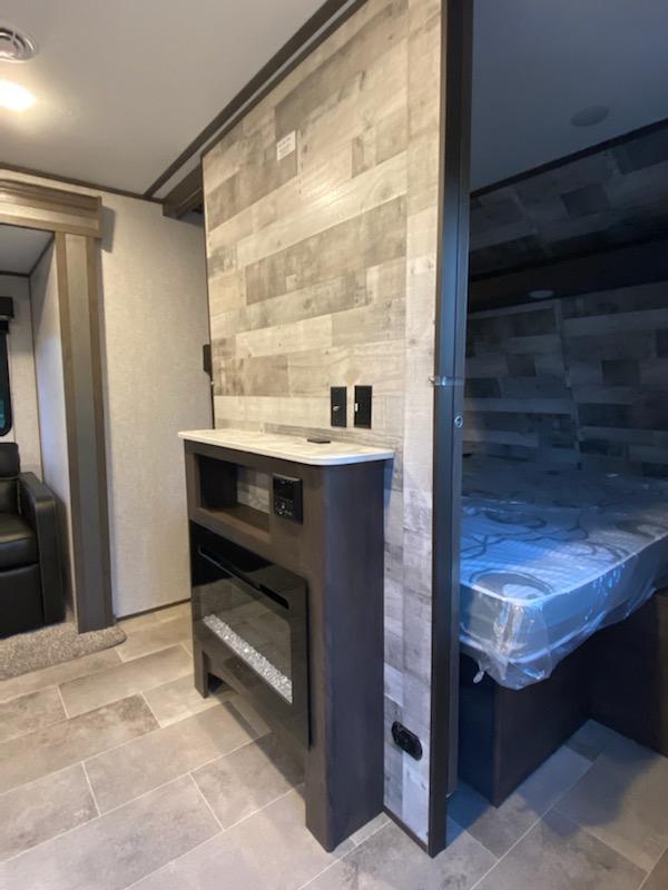 Modern RV rental interior featuring a cozy living space, electric fireplace, and a separated bedroom area.. Other Other 2021