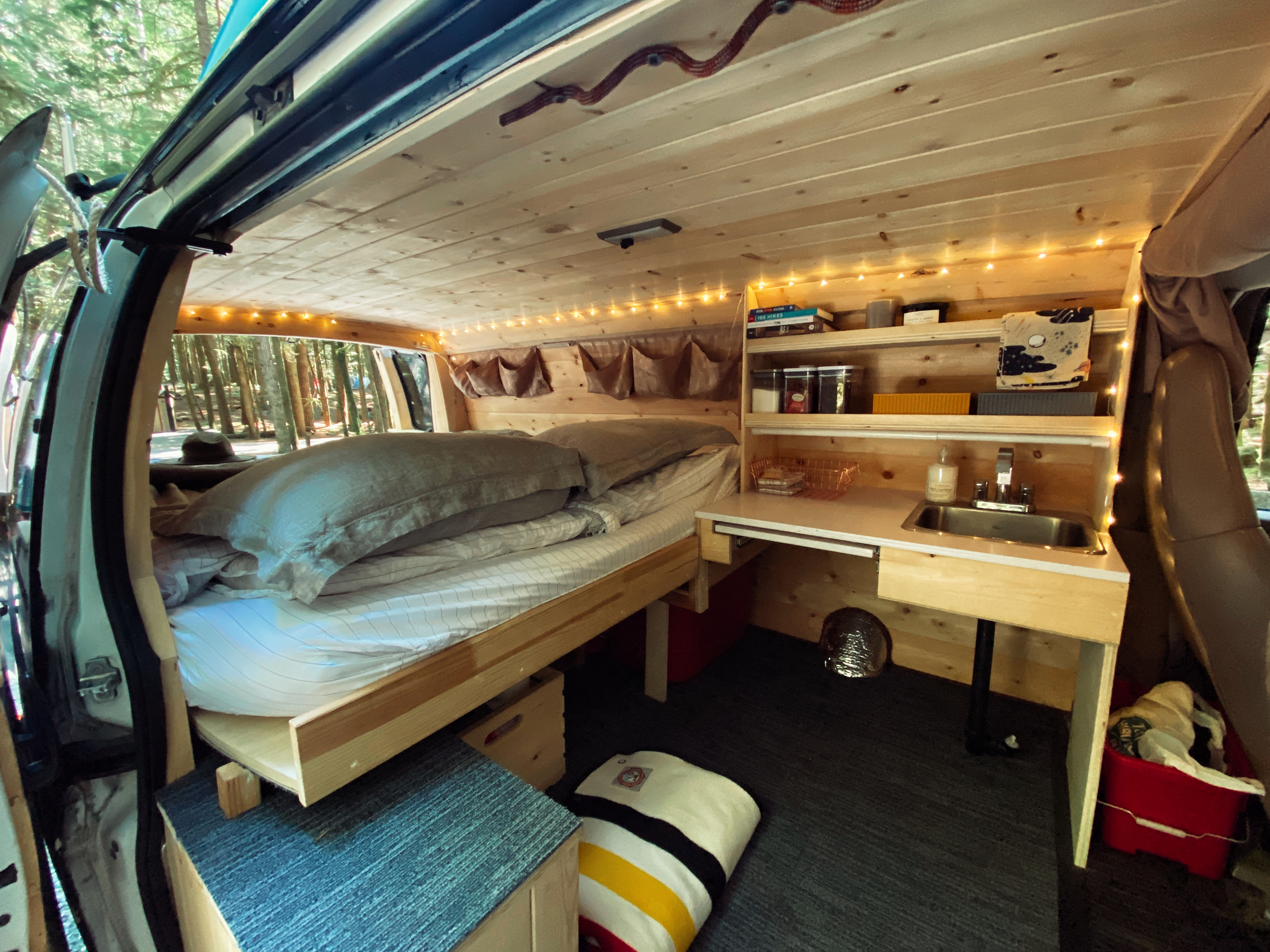 Experience comfort in this RV rental! Features a cozy bed, wood-paneled interior, compact kitchen, and ambient lighting.. Chevrolet Express 2004