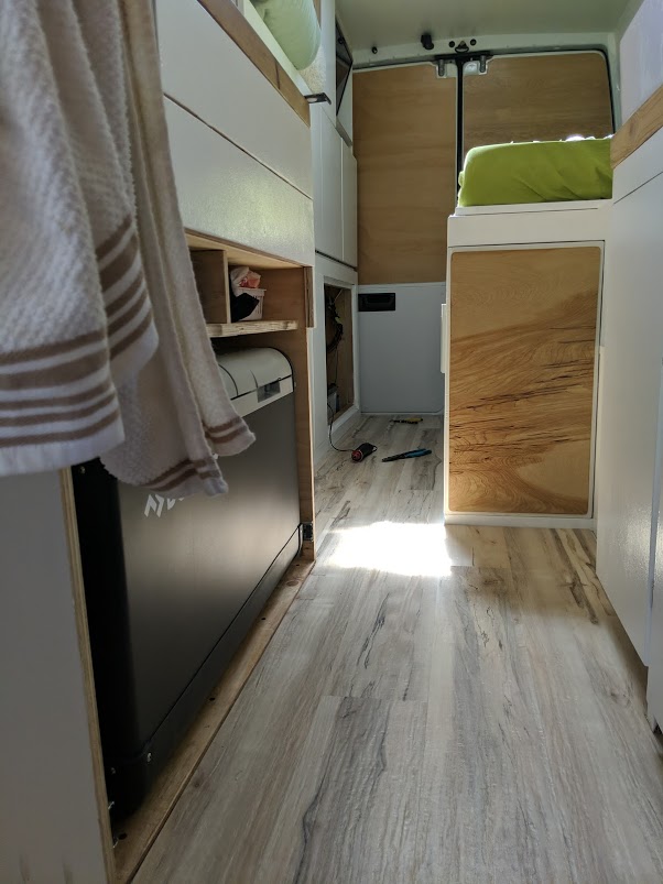 Inside a modern RV rental camper van, featuring a fridge, wood paneling, and custom cabinetry.. Mercedes sprinter 2006