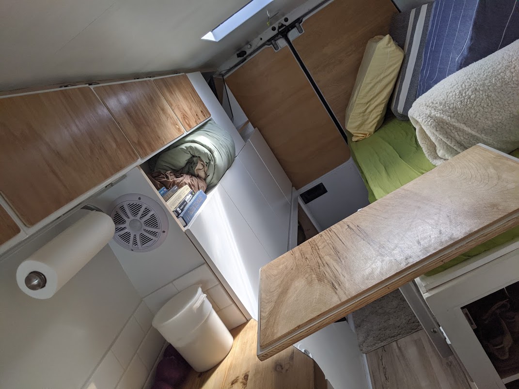 RV rental interior showcasing smart storage, cozy bed, and practical kitchenette features within a compact van.. Mercedes sprinter 2006