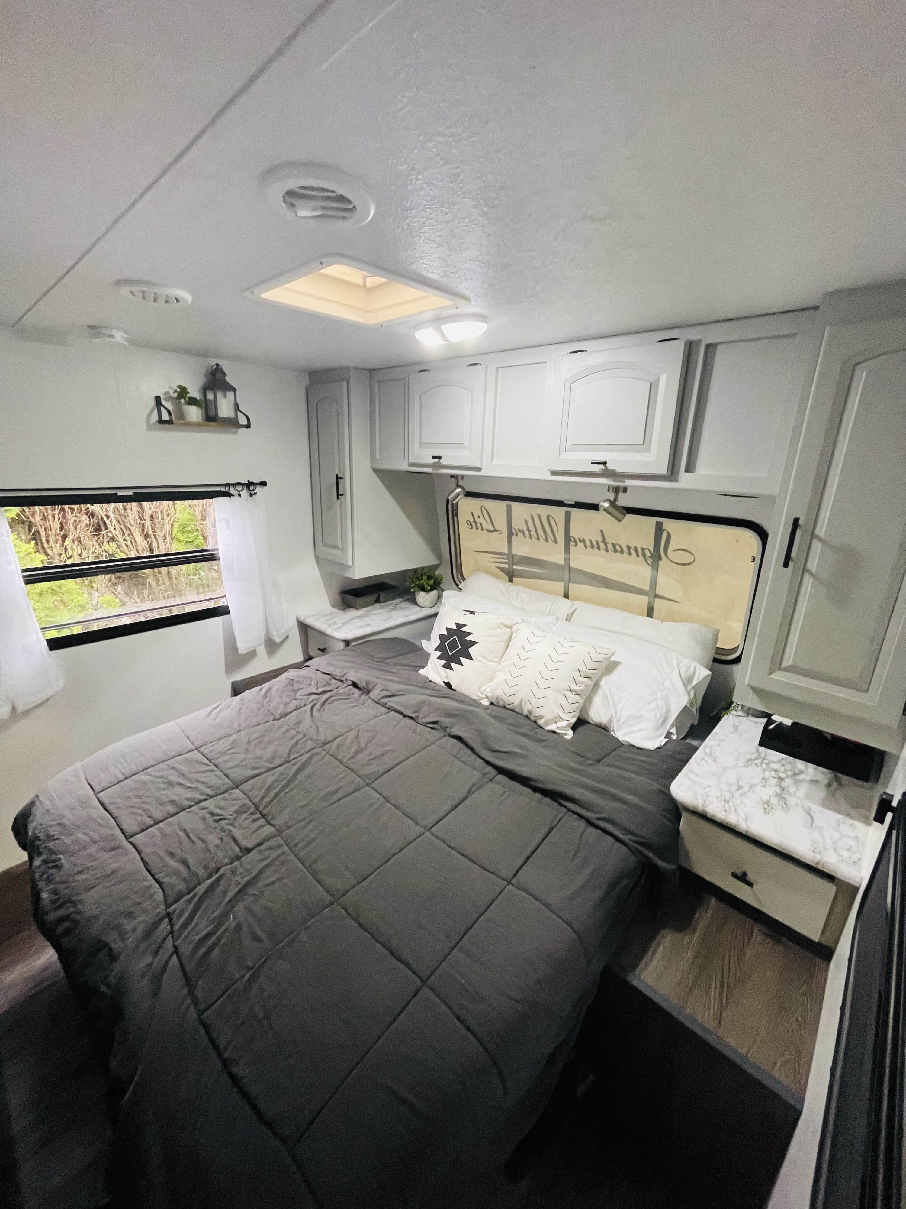 Cozy RV rental bedroom with a gray bed, white cabinets, and bright lighting. Ideal for road trips!. Forest River Rockwood Signature Ultra 2014