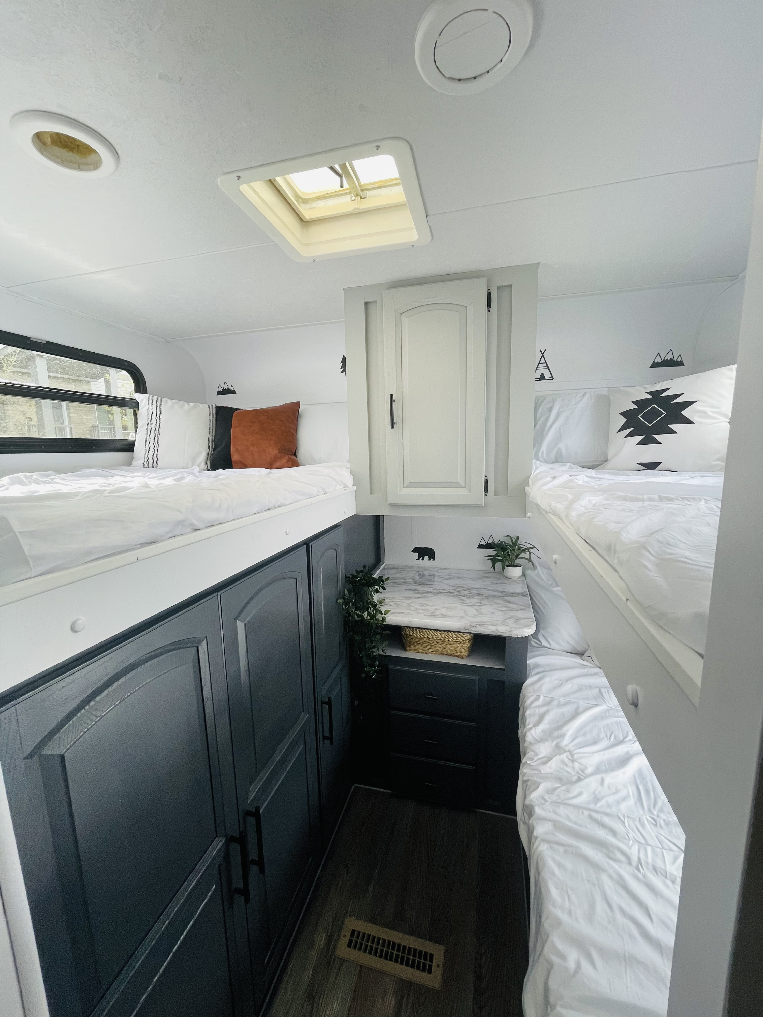 Bright RV rental interior featuring two comfortable bunk beds, sleek dark storage cabinets, and a central counter space.. Forest River Rockwood Signature Ultra 2014