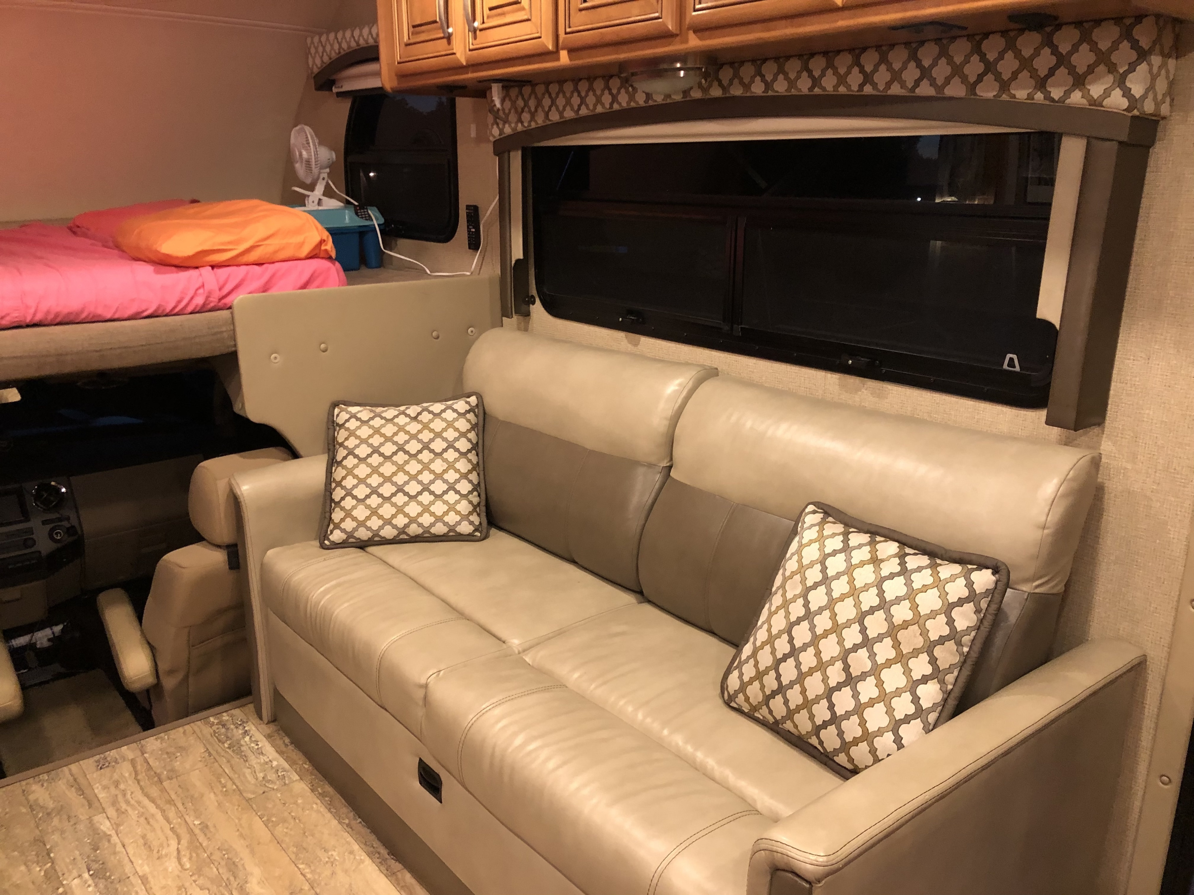 Inviting RV rental living space with a comfy bunk bed, plush leather sofa, and wood cabinets, offering cozy comfort.. Thor Chateau 2017