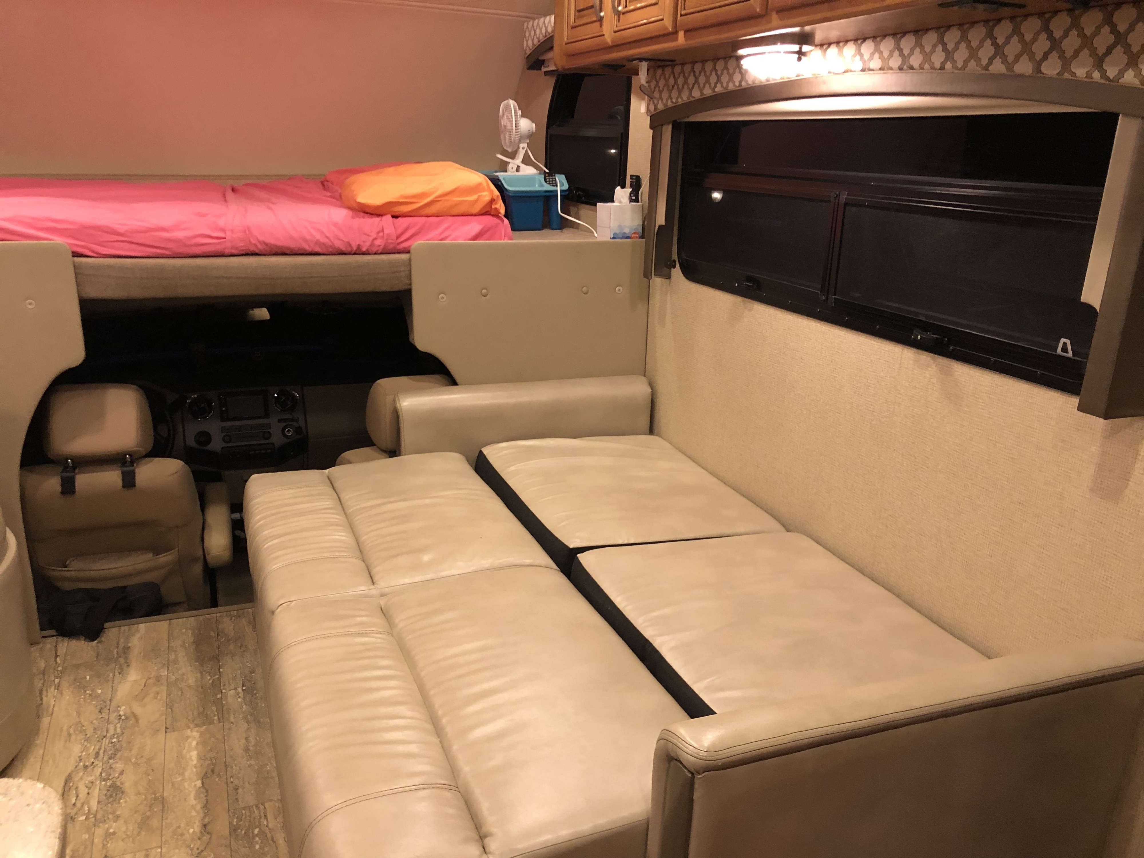 Experience comfort in this RV rental interior, featuring a bunk bed, driver's area, and a versatile couch for seating or sleeping.. Thor Chateau 2017