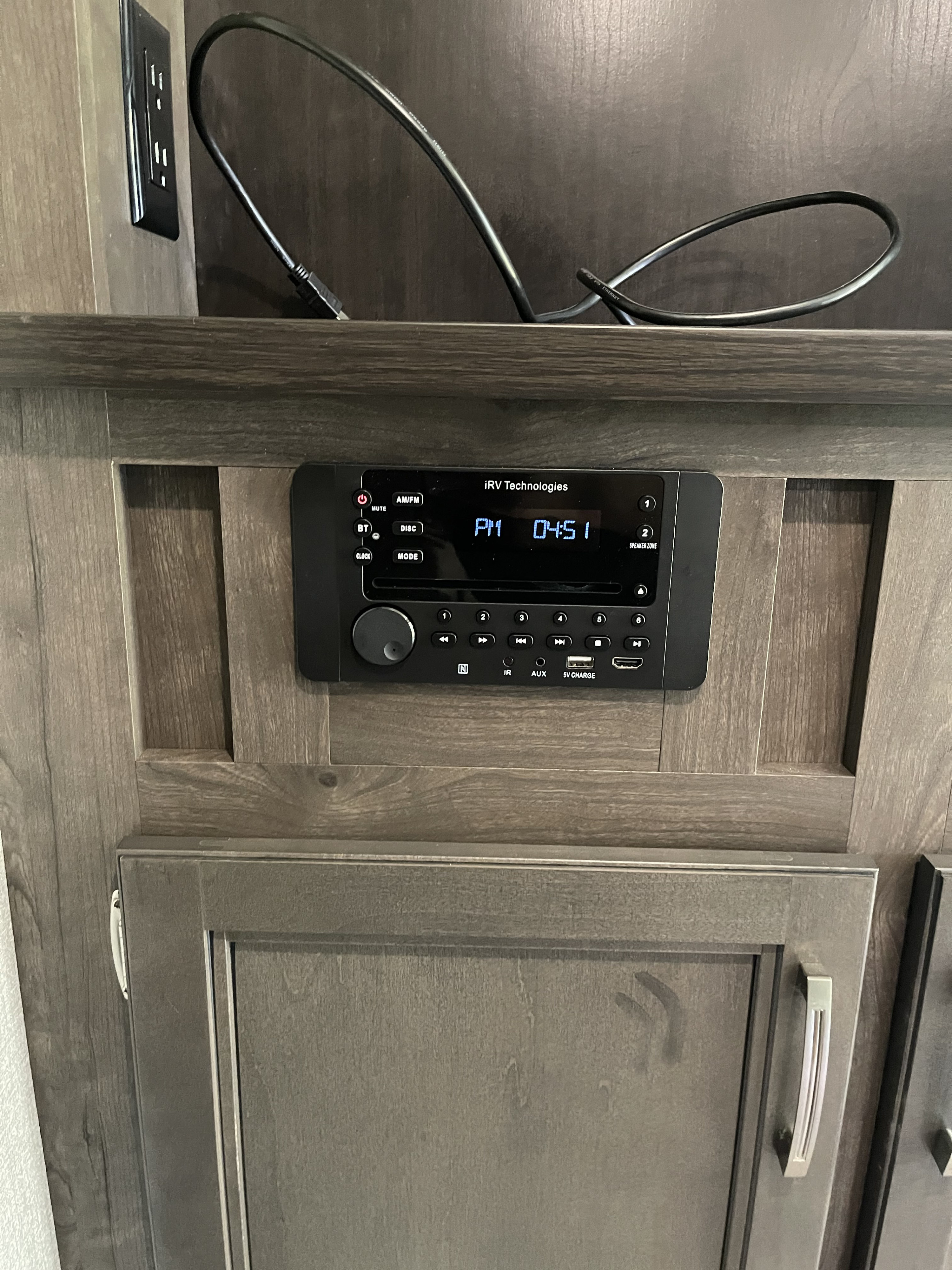 RV rental interior featuring an iRV Technologies media system with clock (4:51 PM), power outlet, and wood cabinets.. Jayco Jay Flight Swift 2021