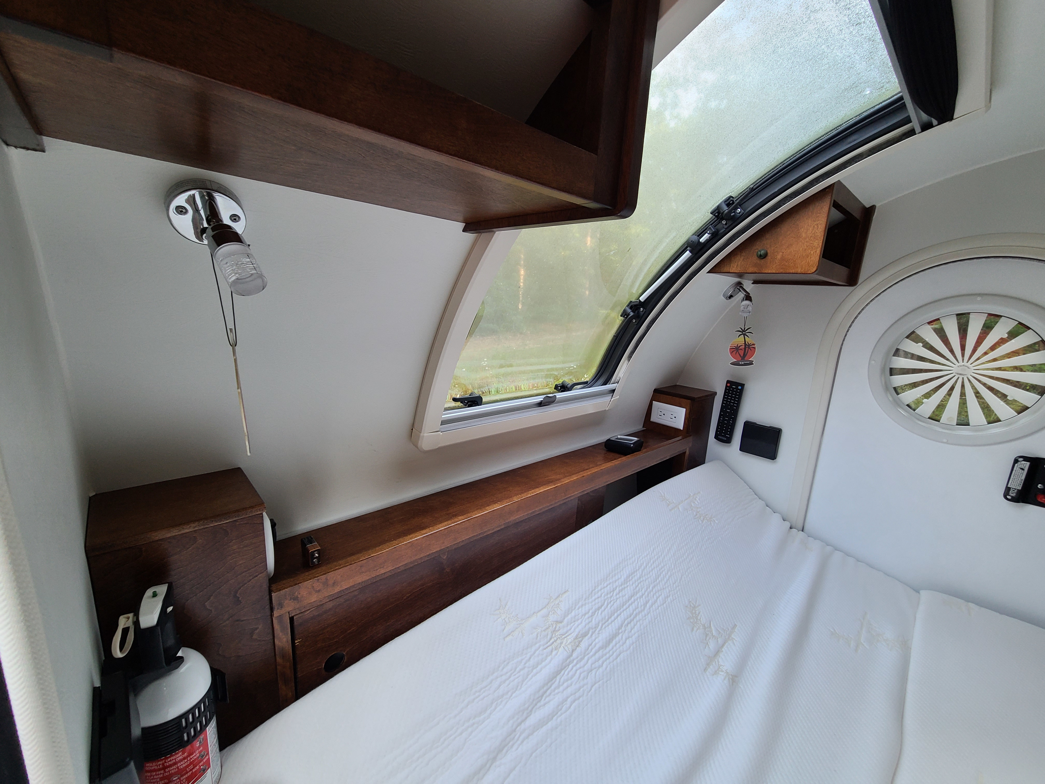 Cozy RV rental interior: a compact bedroom features a bed, wooden storage, a large window, and essential controls.. Nucamp Tag 2018
