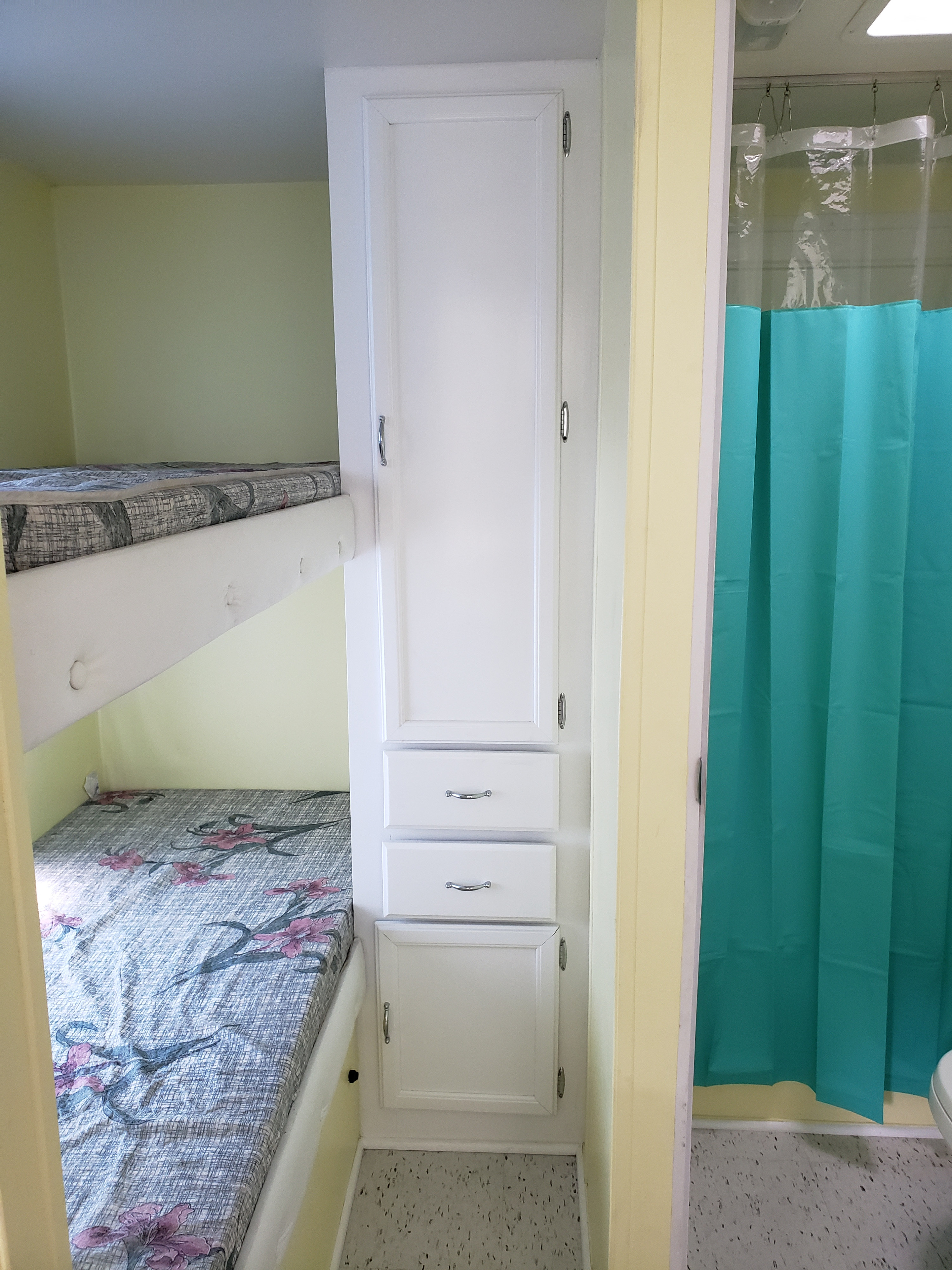 RV rental interior showcasing bunk beds, integrated white storage cabinets, and a compact shower with a teal curtain.. Forest River Salem 1998