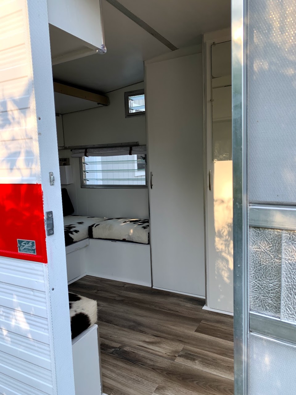 Inviting RV rental interior: wood floors, white cabinetry, and cozy cowhide pattern cushions create a stylish space.. Shasta Compact 1968