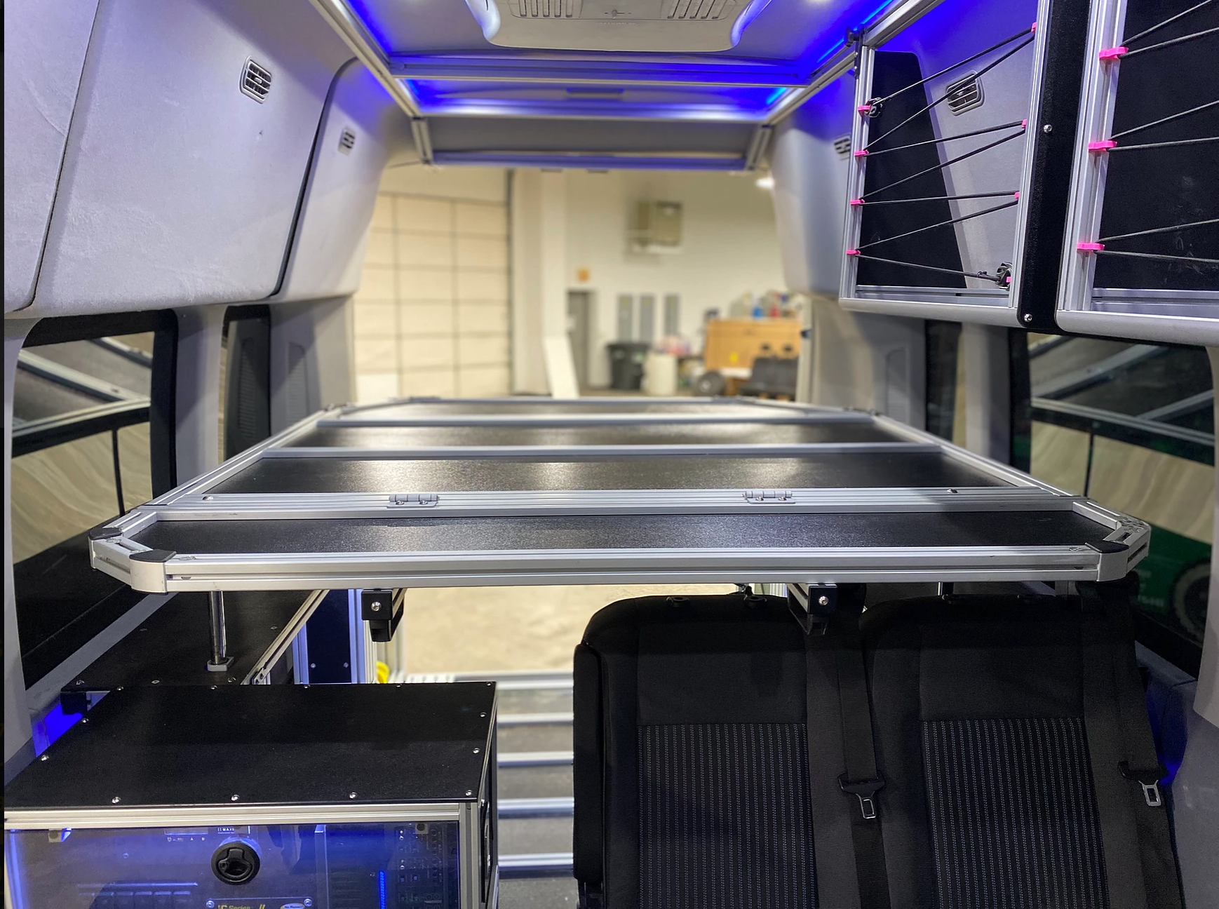 Inside an rv rental: a flexible multi-purpose platform above rear seats, storage, and a custom tech setup.. Ford Van 2017