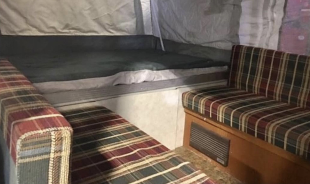 RV rental: Compact pop-up camper interior with a bed area and two plaid dinette benches. Ideal for camping.. Coleman Destiny Taos 1999