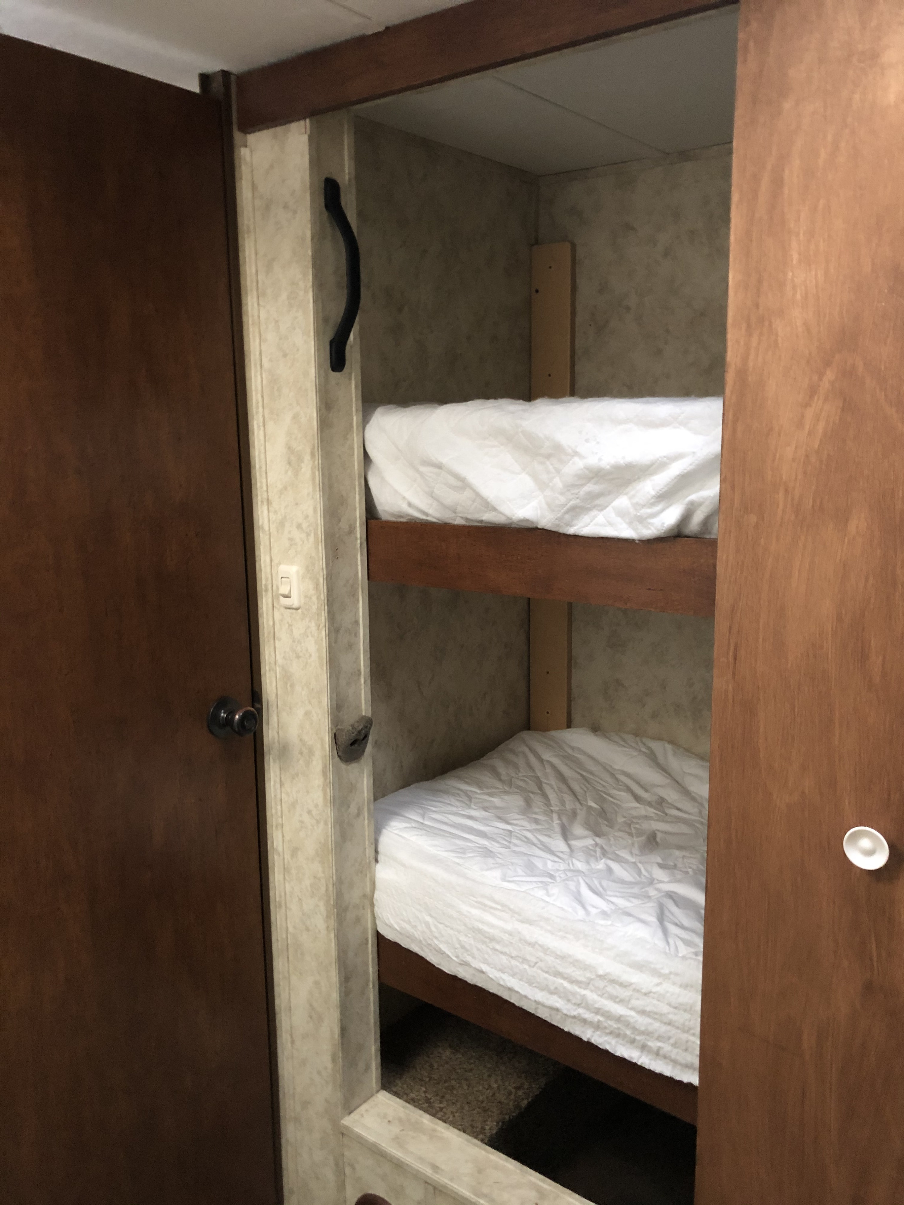 An RV rental interior featuring cozy bunk beds with white bedding, a compact sleeping solution for adventures.. Coachmen Chaparral 2011