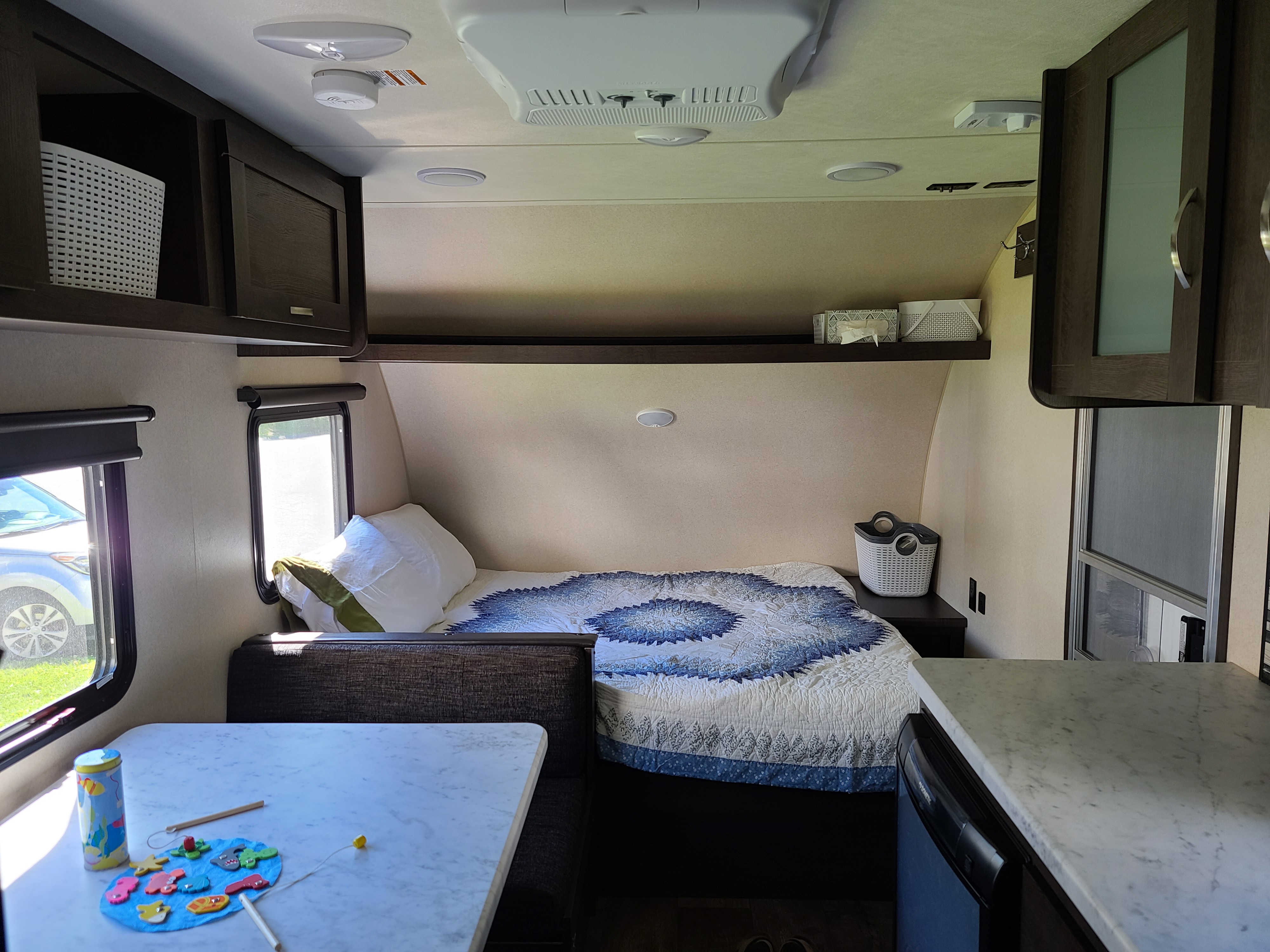 Inside a compact RV rental: a cozy bed with quilt, dining table, and built-in storage optimize living space.. Forest River Salem 2019